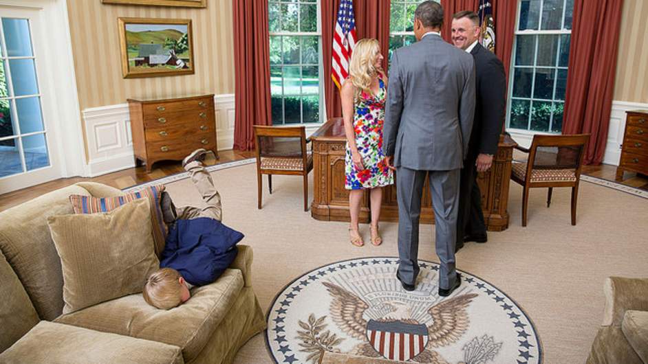 President Barack Obama visits with a departing United States Secret Service agent and his wife as their son dives into a couch in the Oval Office, June 23, 2014.