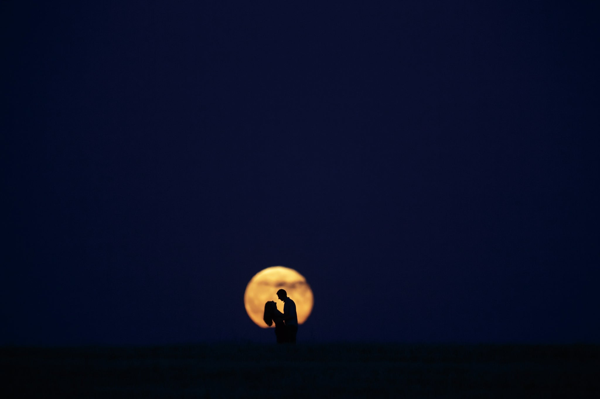 A couple stand in front of the full moon in Burgos, Spain, on 9 September 2014