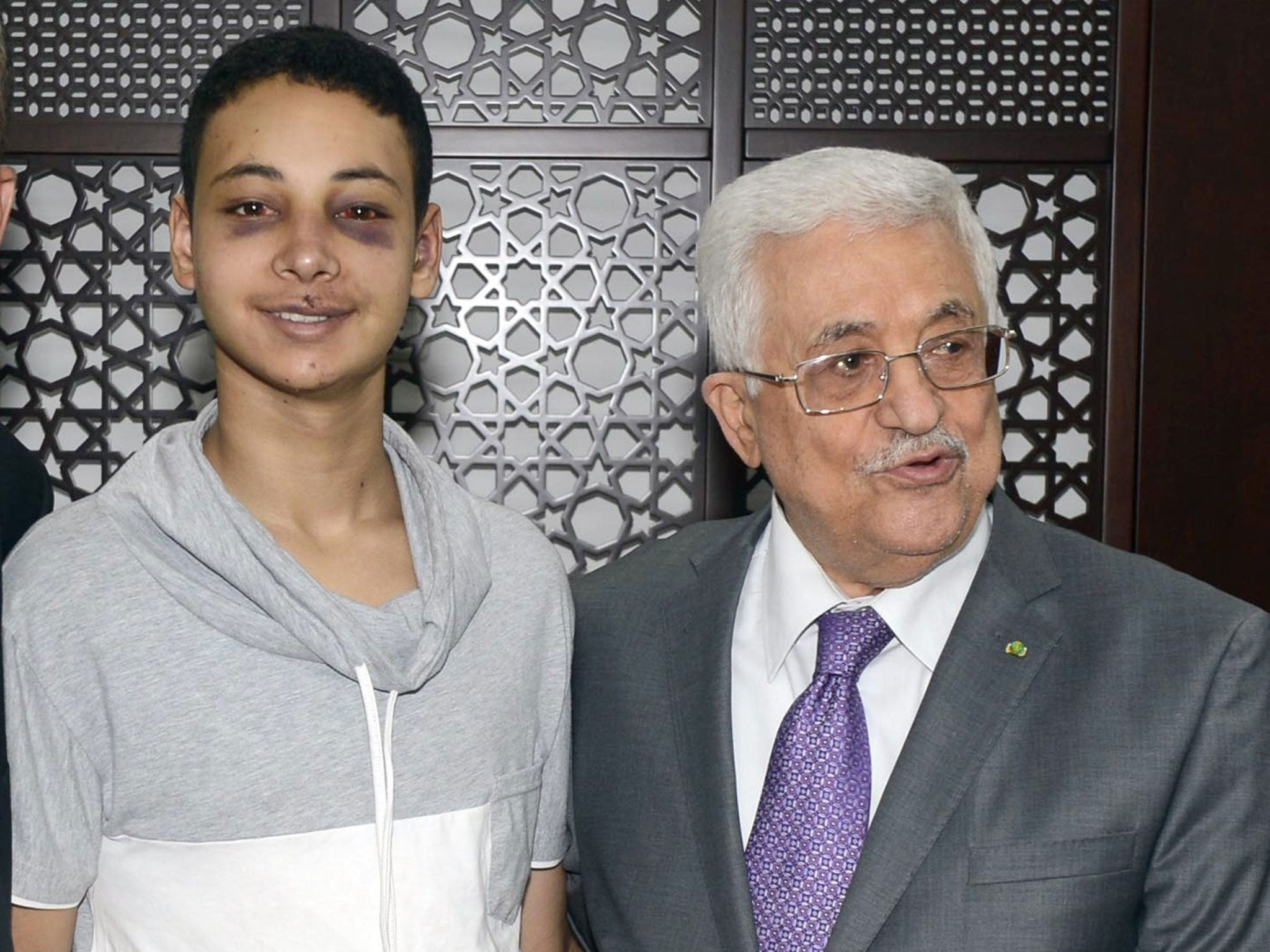 Palestinian President Mahmoud Abbas (R) stands with Tariq Khdeir as he meets with family members of Palestinian teen Mohammed Abu Khdeir in the West Bank city of Ramallah