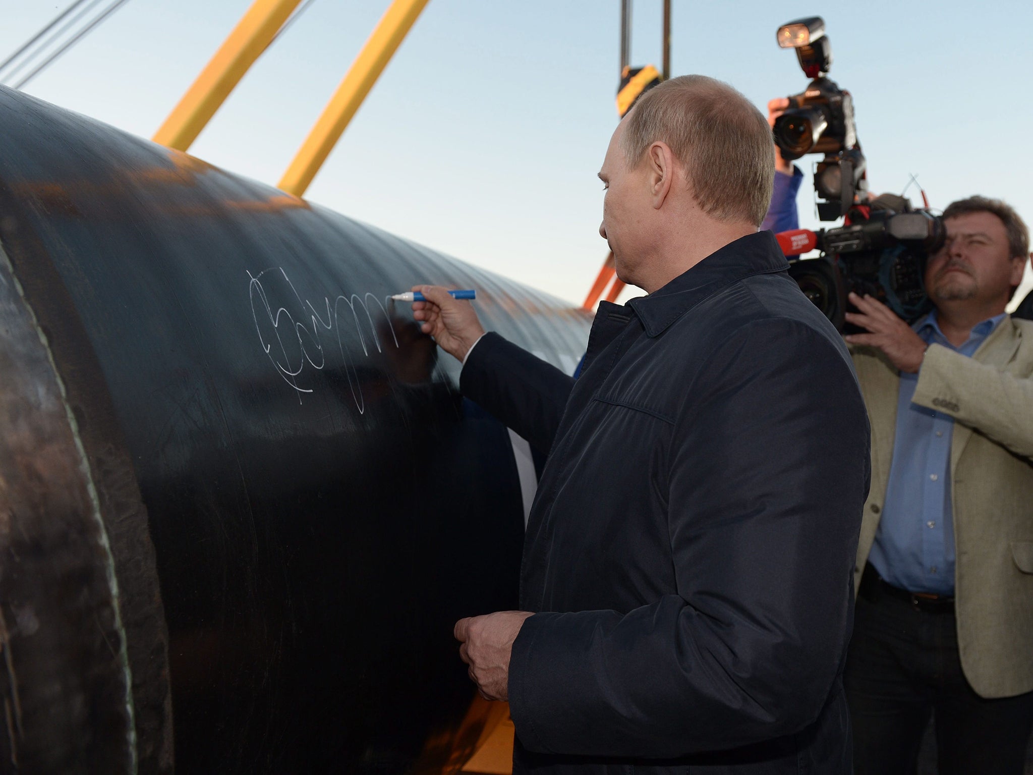 Russian President Vladimir Putin leaves his signature on the symbolicaly joined pipes at the ceremony marking the joining of the first link in the Power of Siberia main gas pipeline