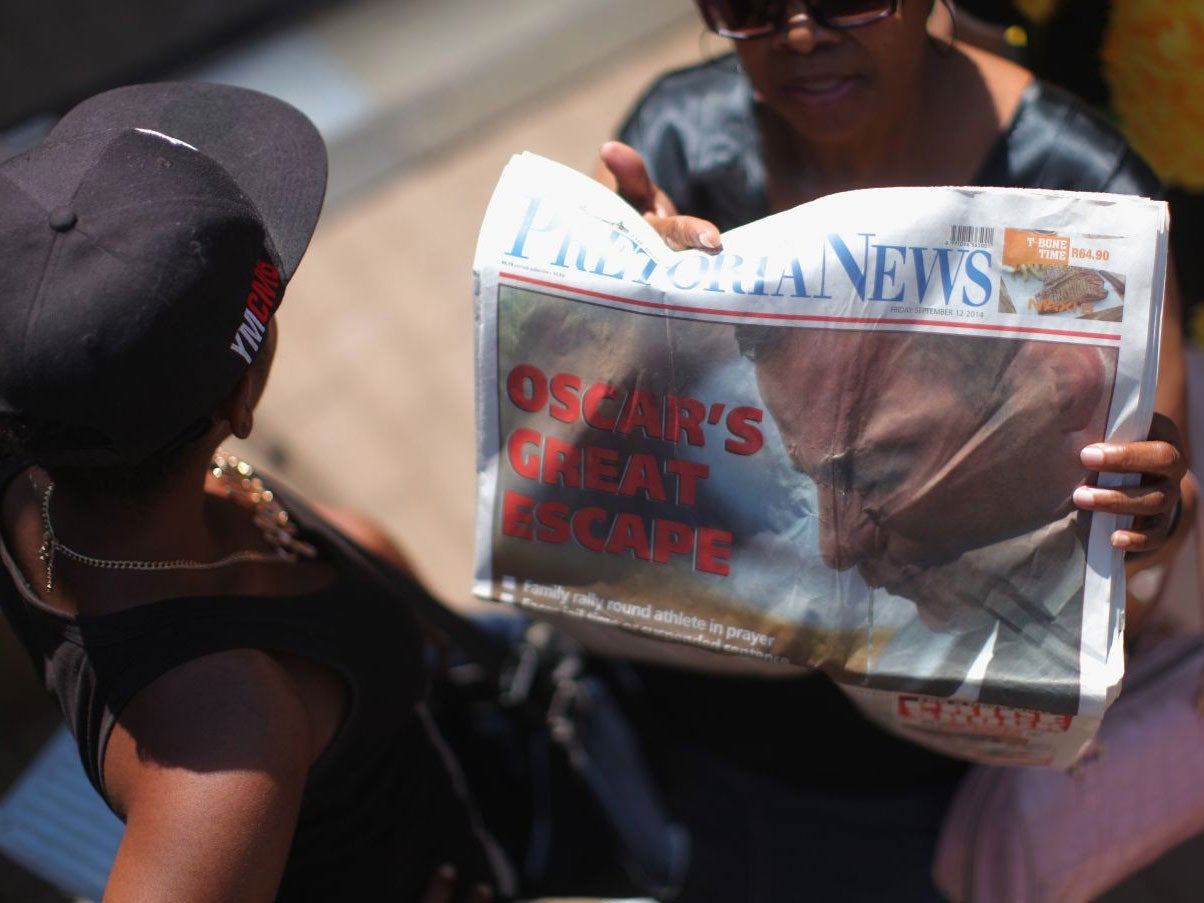 A woman holds a copy of the Pretoria News with the headline 'Oscar's great escape' on 12 September