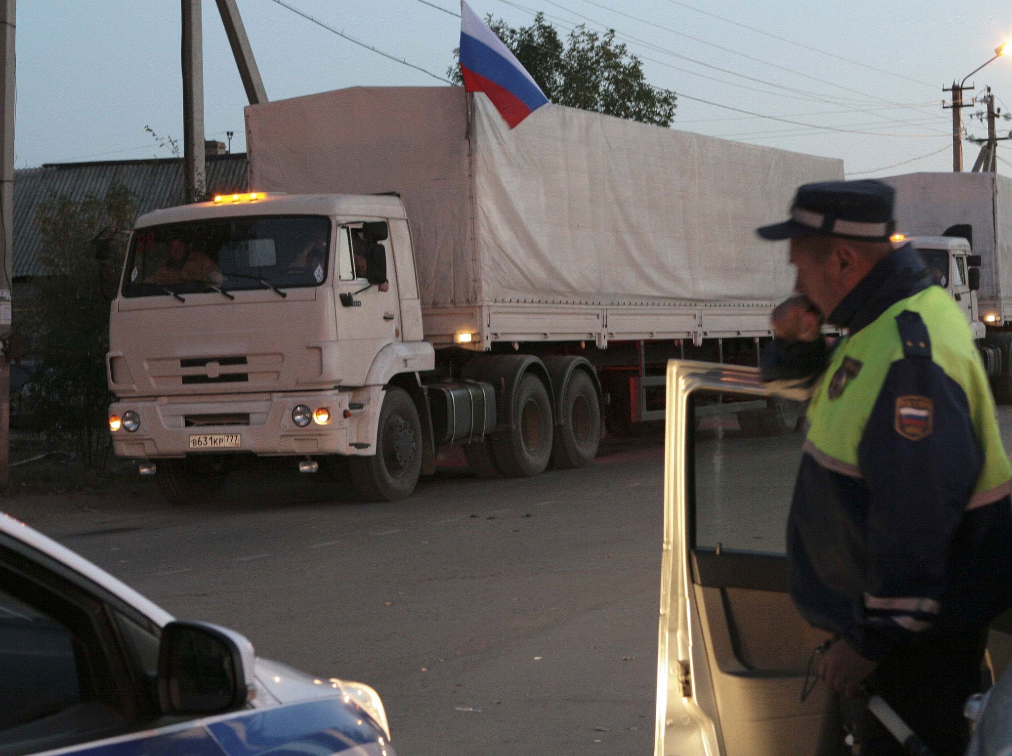 Trucks from a Russian convoy carrying humanitarian aid for Ukraine queue near a police patrol at a Russia-Ukraine border crossing point "Donetsk" in Russia's Rostov Region.