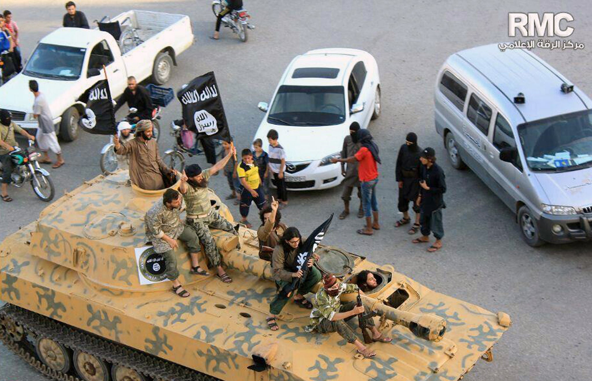 Fighters from Islamic State group sit on their tank during a parade in Raqqa, Syria