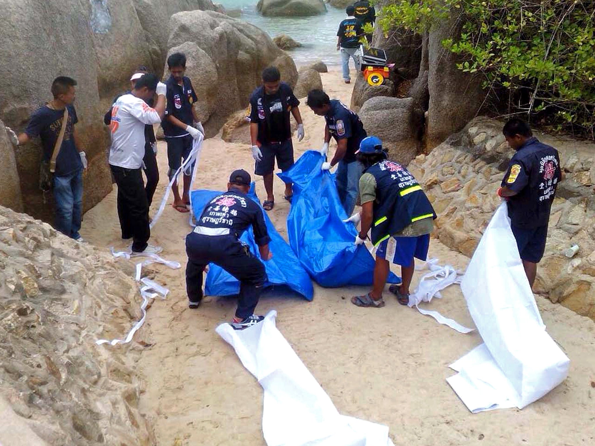 Thai workers carry the bodies of two British tourists on Koh Tao island in the Surat Thani province of southern Thailand