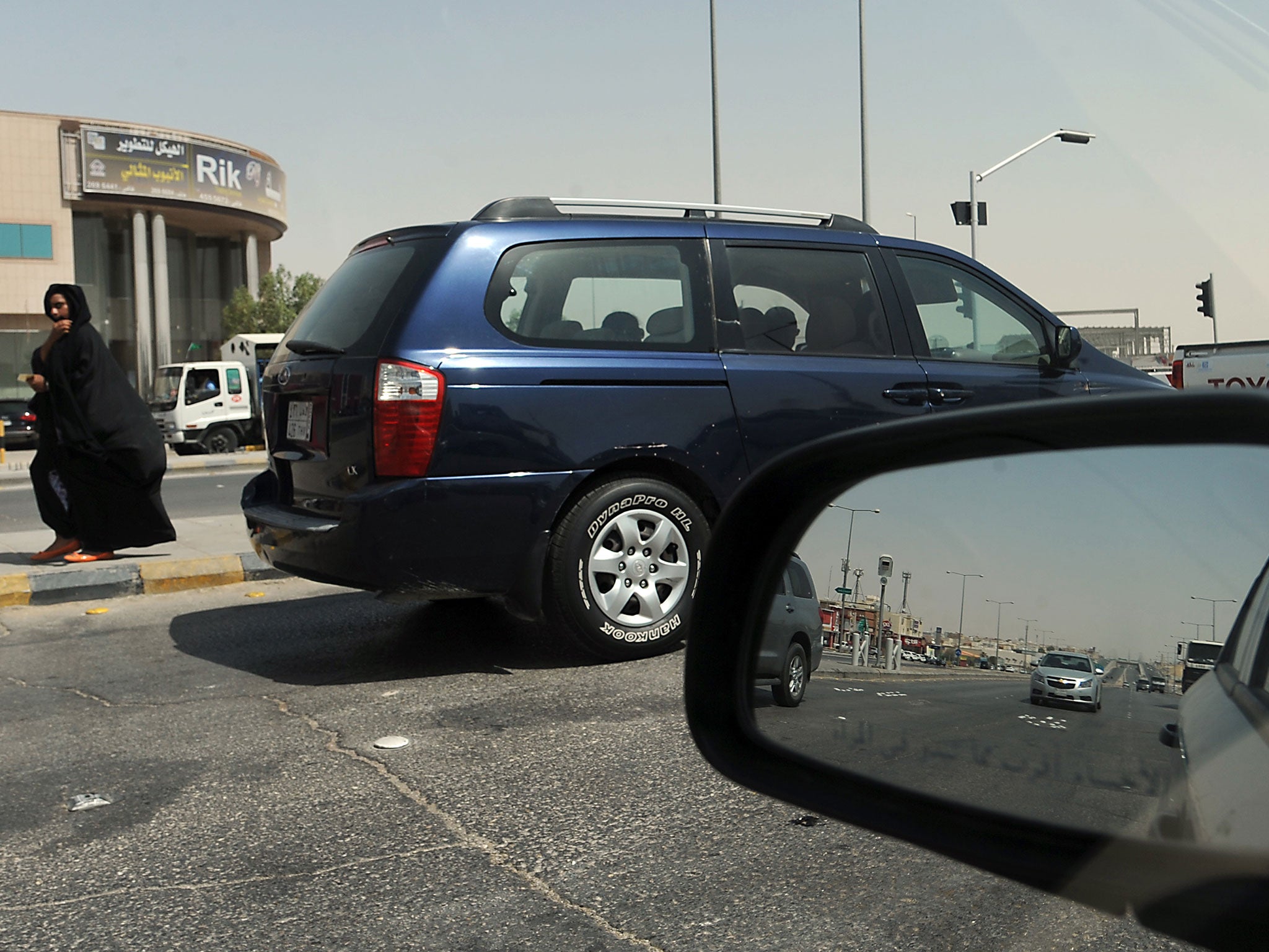 A Saudi woman, unrelated to the incident, walks past stopping vehicles