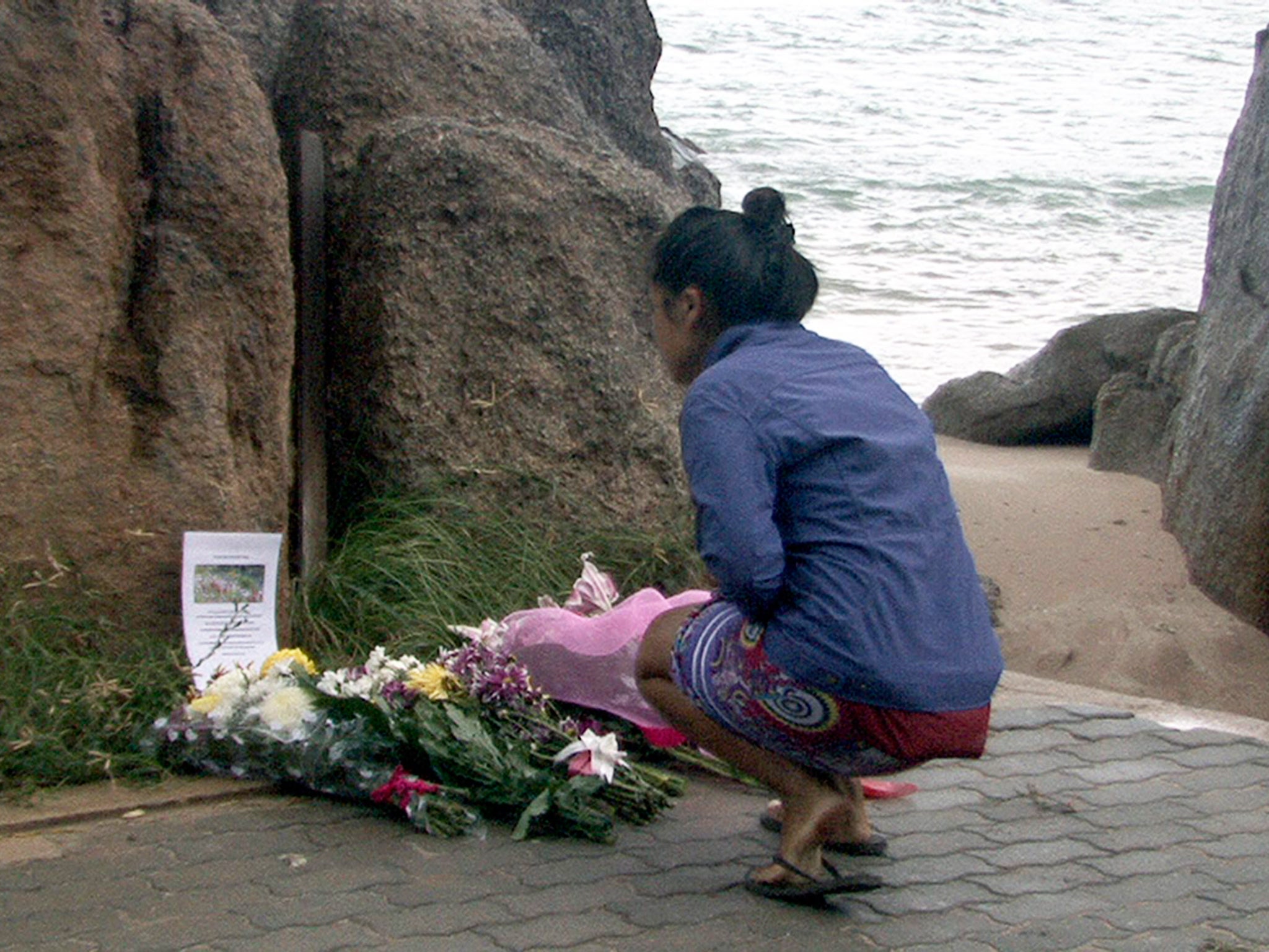 A Thai villager lays flowers during a memorial service for two murdered British tourists at the crime scene on a beach of Koh Tao resort island