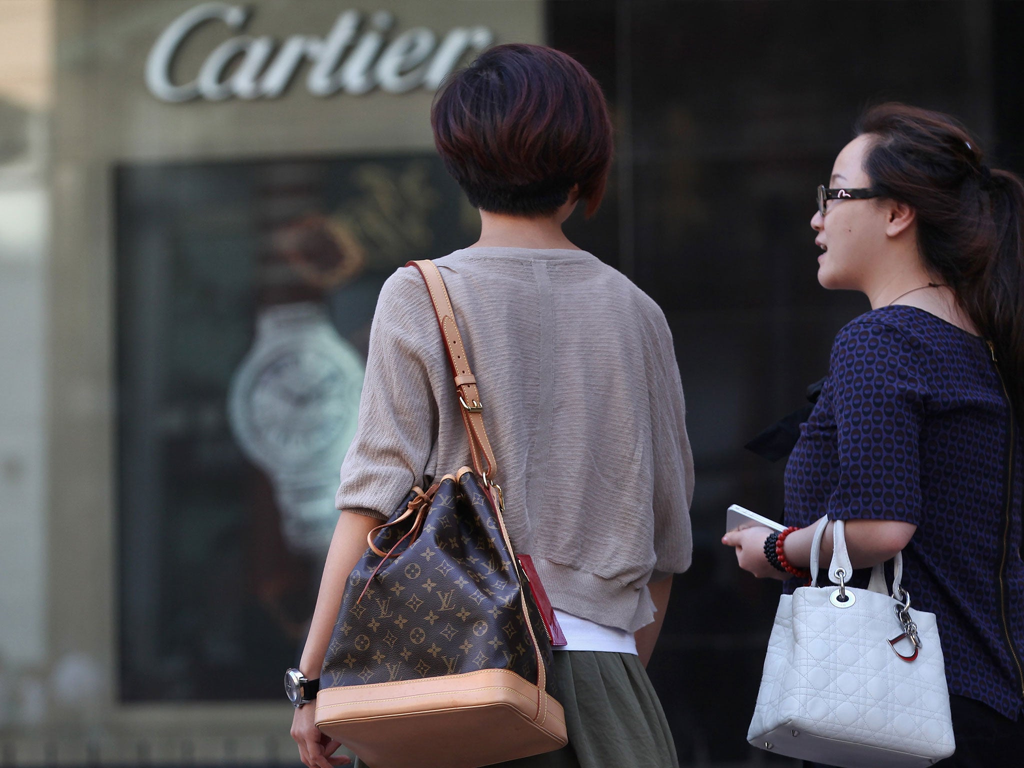 Chinese women walk past the Cartier store on June 11, 2012 in Beijing, China.