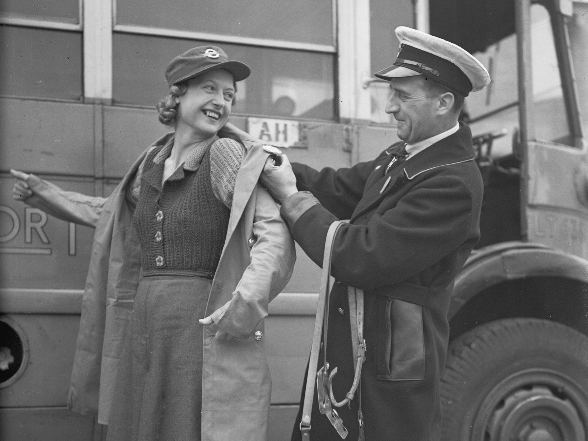 Lend a hand: a 'clippie', (female bus conductor) is helped into her uniform by a bus driver in 1941 (Getty Images)