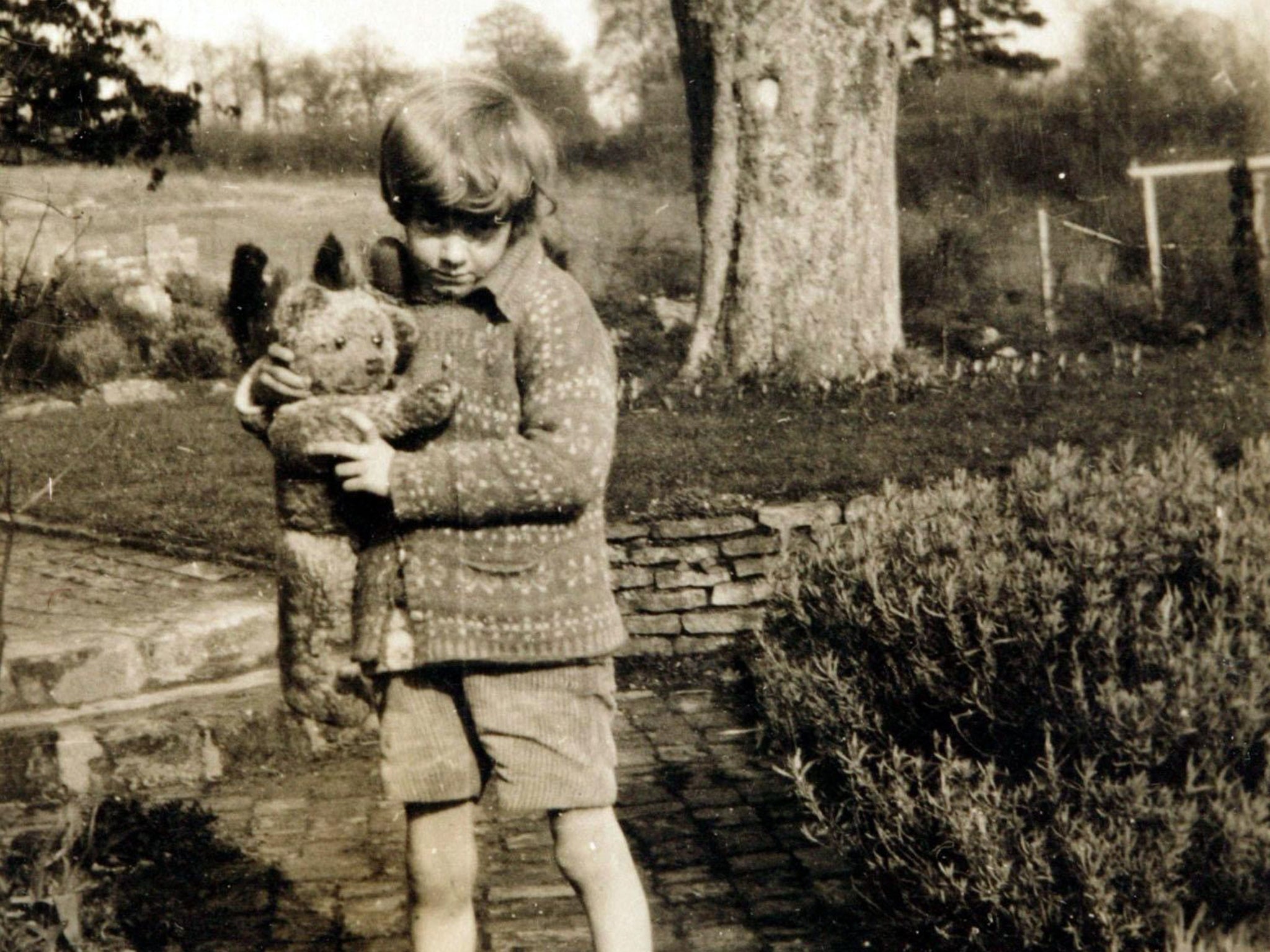 Christopher Robin clutching his Winnie the Pooh teddy bear