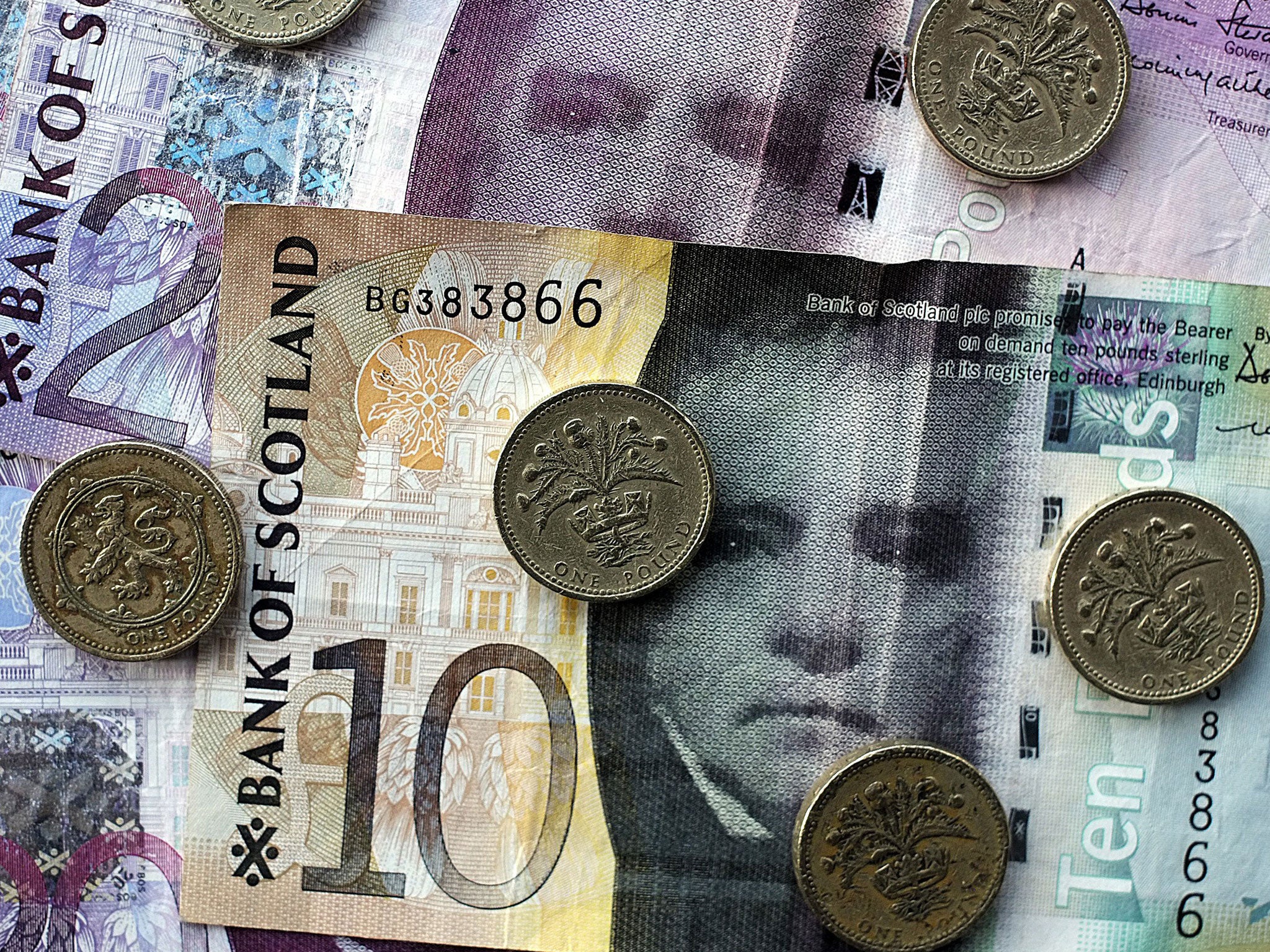 An arrangement of Scottish pound sterling banknotes and pound coins showing the thistle of Scotland