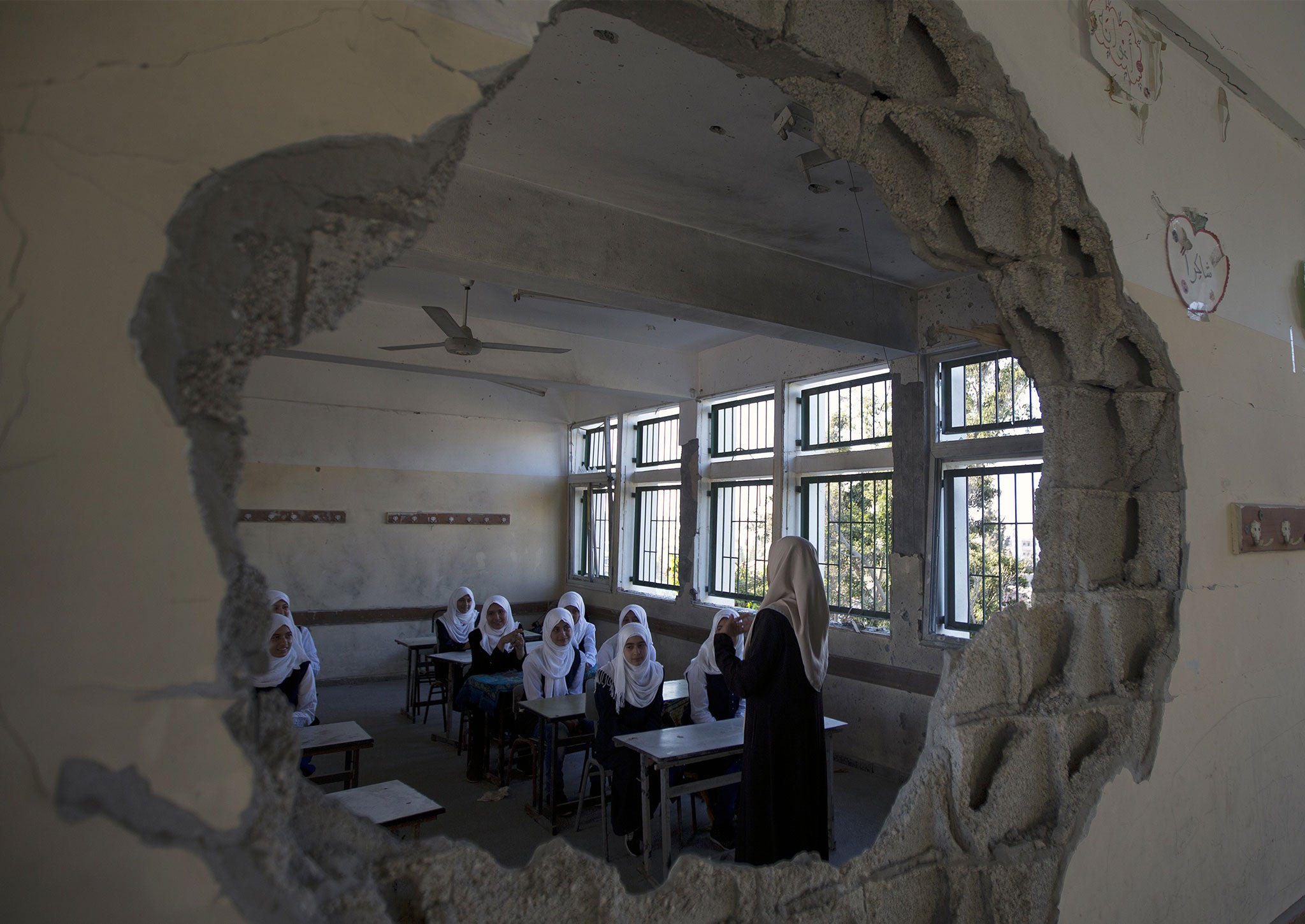 Palestinian students are seen through a damaged sitting in a classroom at a goverment school in the Shejaiya neighbourhood of Gaza City on September 14, 2014