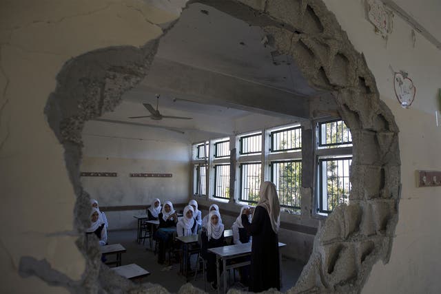 Palestinian students are seen through a damaged sitting in a classroom at a goverment school in the Shejaiya neighbourhood of Gaza City on September 14, 2014