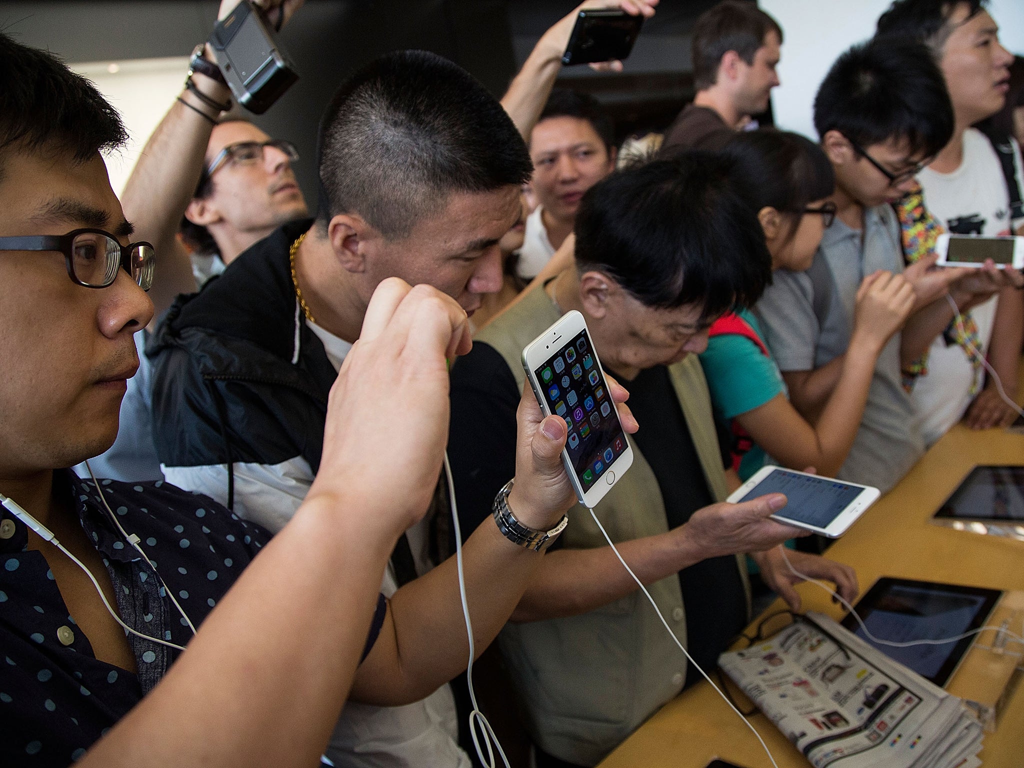 Customers look at the new iPhones on display at the launch of the new Apple iPhone 6 and iphone 6 plus at the Apple IFC store in Hong Kong