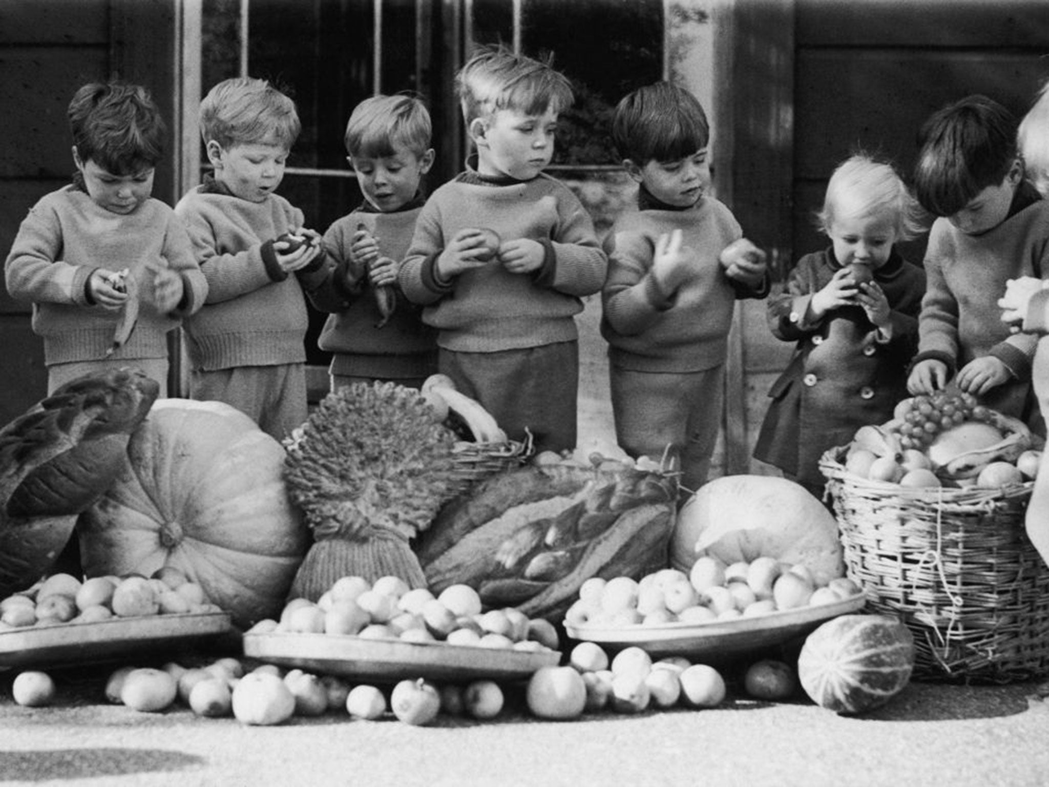 Children at the Leytonstone branch of the Homeless Children's Aid and Adoption Society tuck into their harvest festival gifts, in October 1936