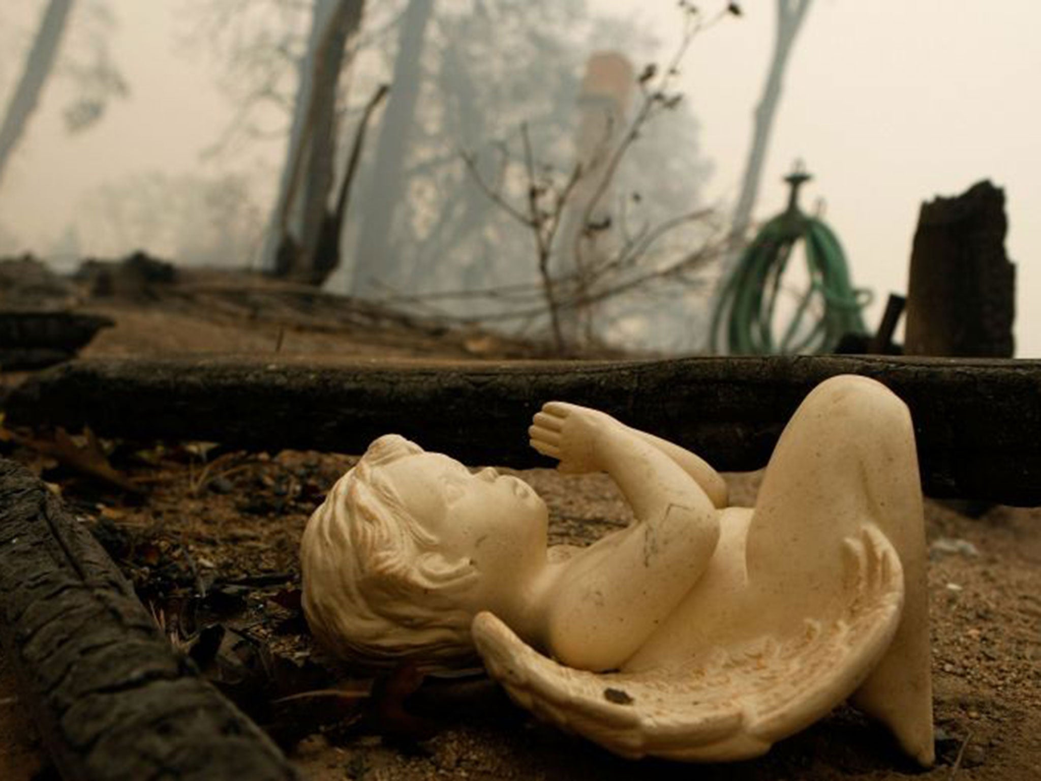 A ceramic figure is the only thing remaining at the site of this destroyed home in Fredalba, California. The dry Santa Ana winds roll into Southern California from the upper Mojave Desert, setting off car alarms and starting wildfires