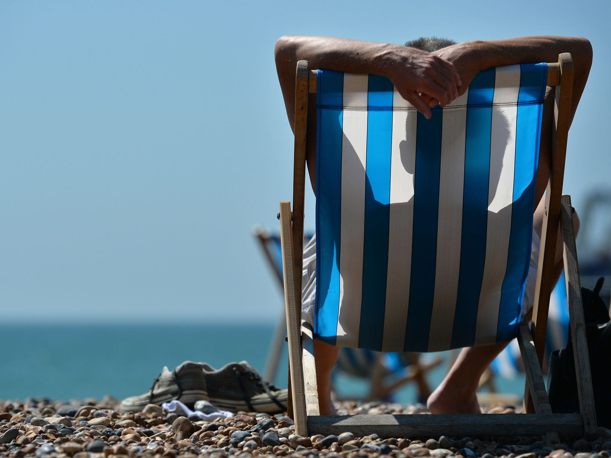 A man relaxes on a deckchair on the beach in Brighton, on the south coast during hot weather
