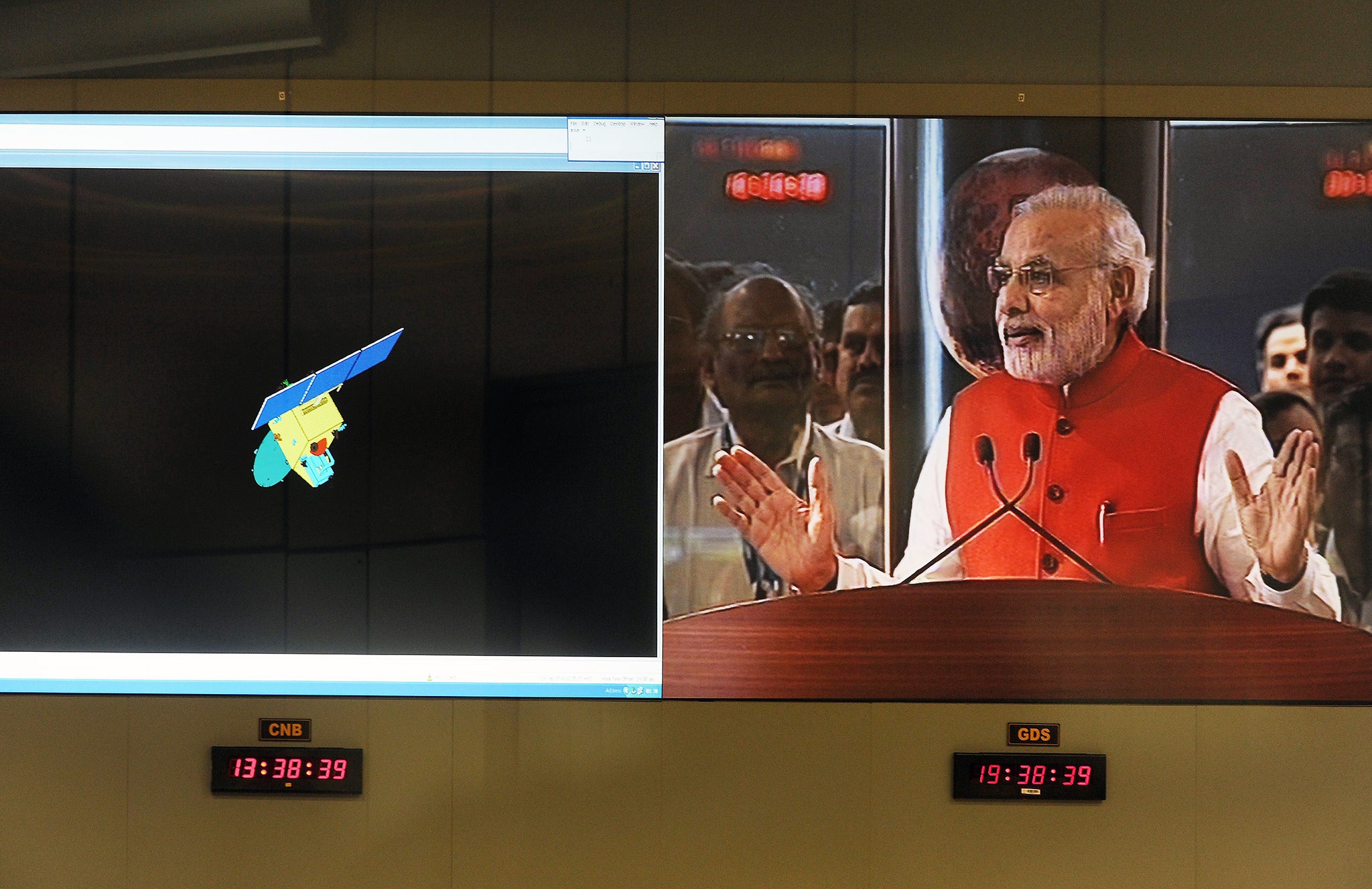 Indian Prime Minister Narendra Modi is seen on a screen as he addresses scientists alongside a graphic of the Mars Orbiter Spacecraft (MoM), after the spacecraft successfully entered into the Mars orbit, at the Indian Space Research Organisation's (ISRO)