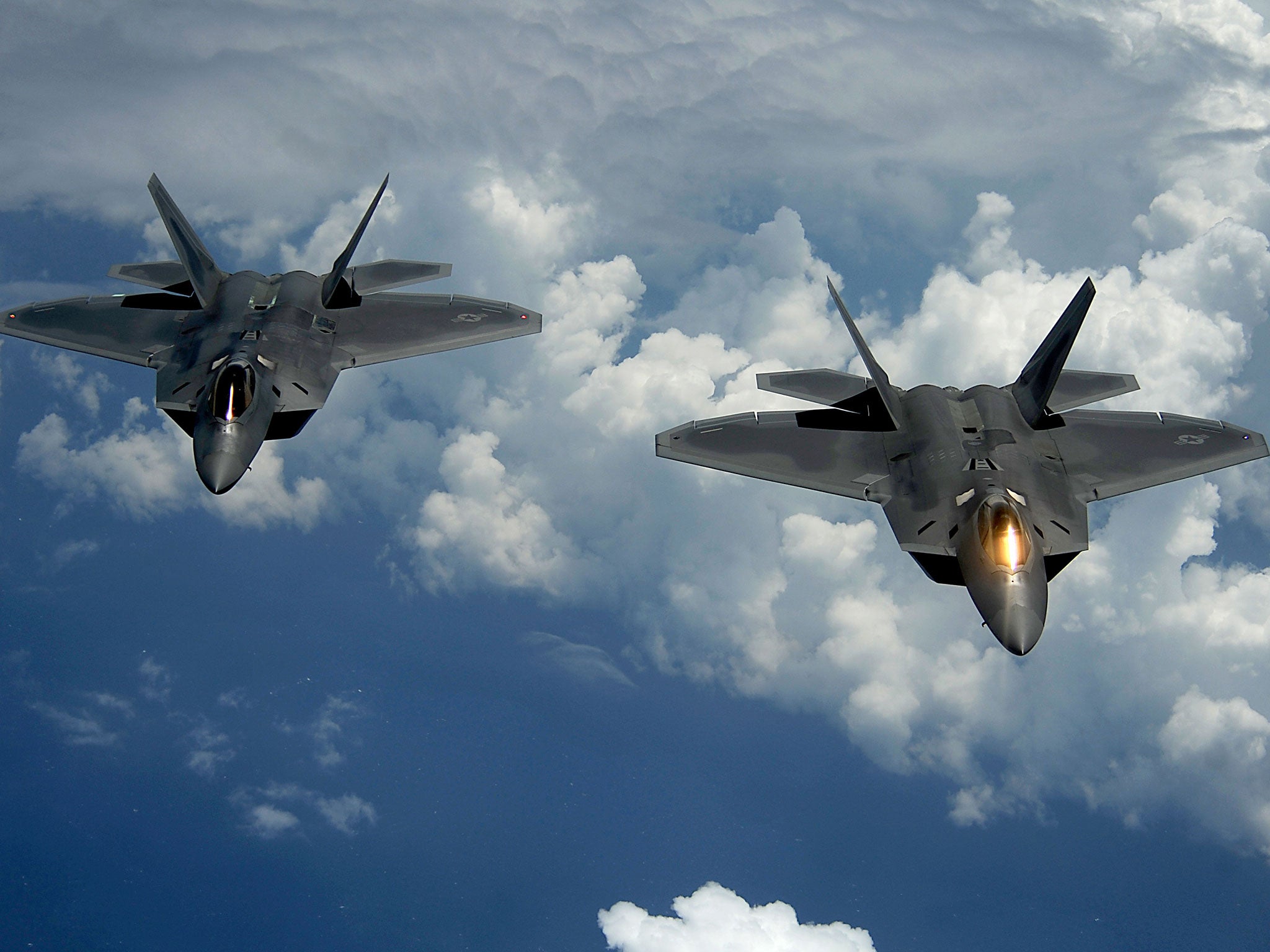 Two US Air Force F-22 Raptor aircraft fly behind a KC-135 Stratotanker aircraft after receiving fuel over Joint Base Andrews, Md, July 2012