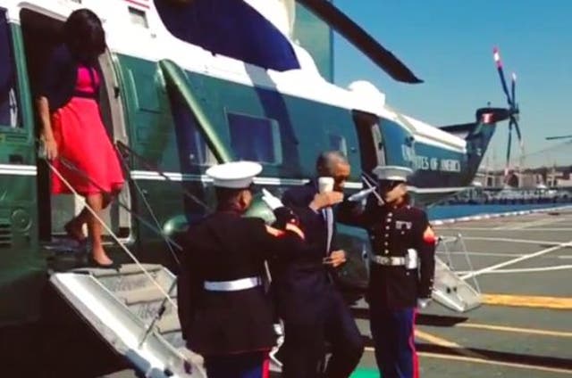 President Barack Obama saluted two Marines while holding a cup yesterday