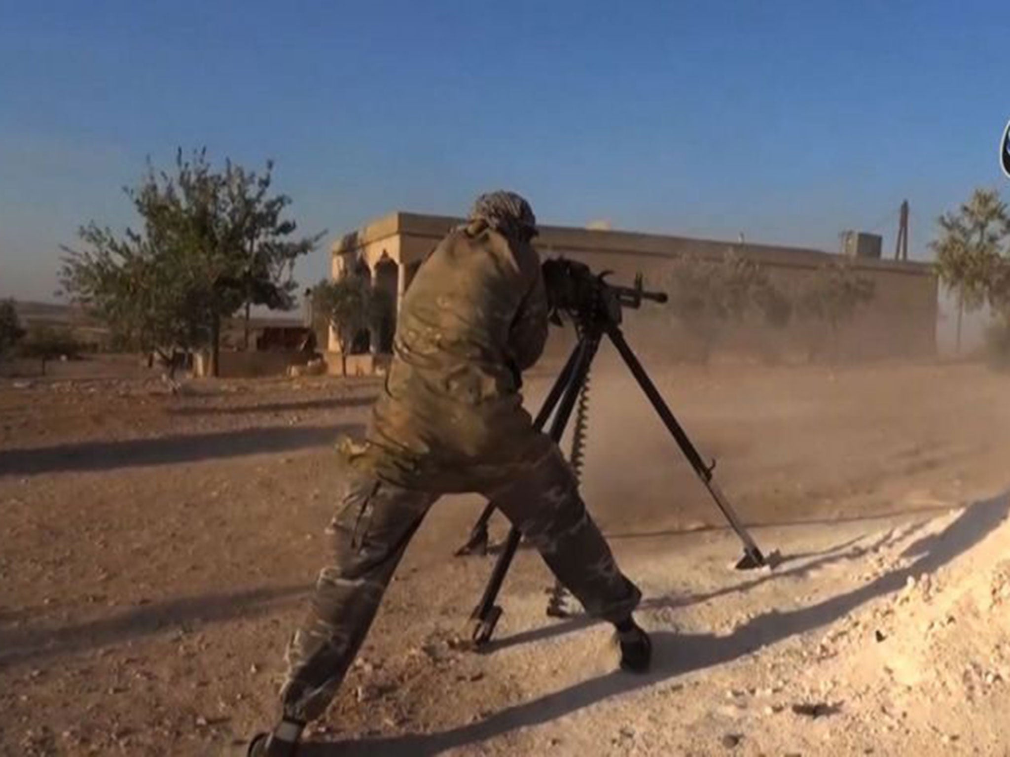 An Isis militant fires a heavy machine gun during fighting near the threatened city of Kobane