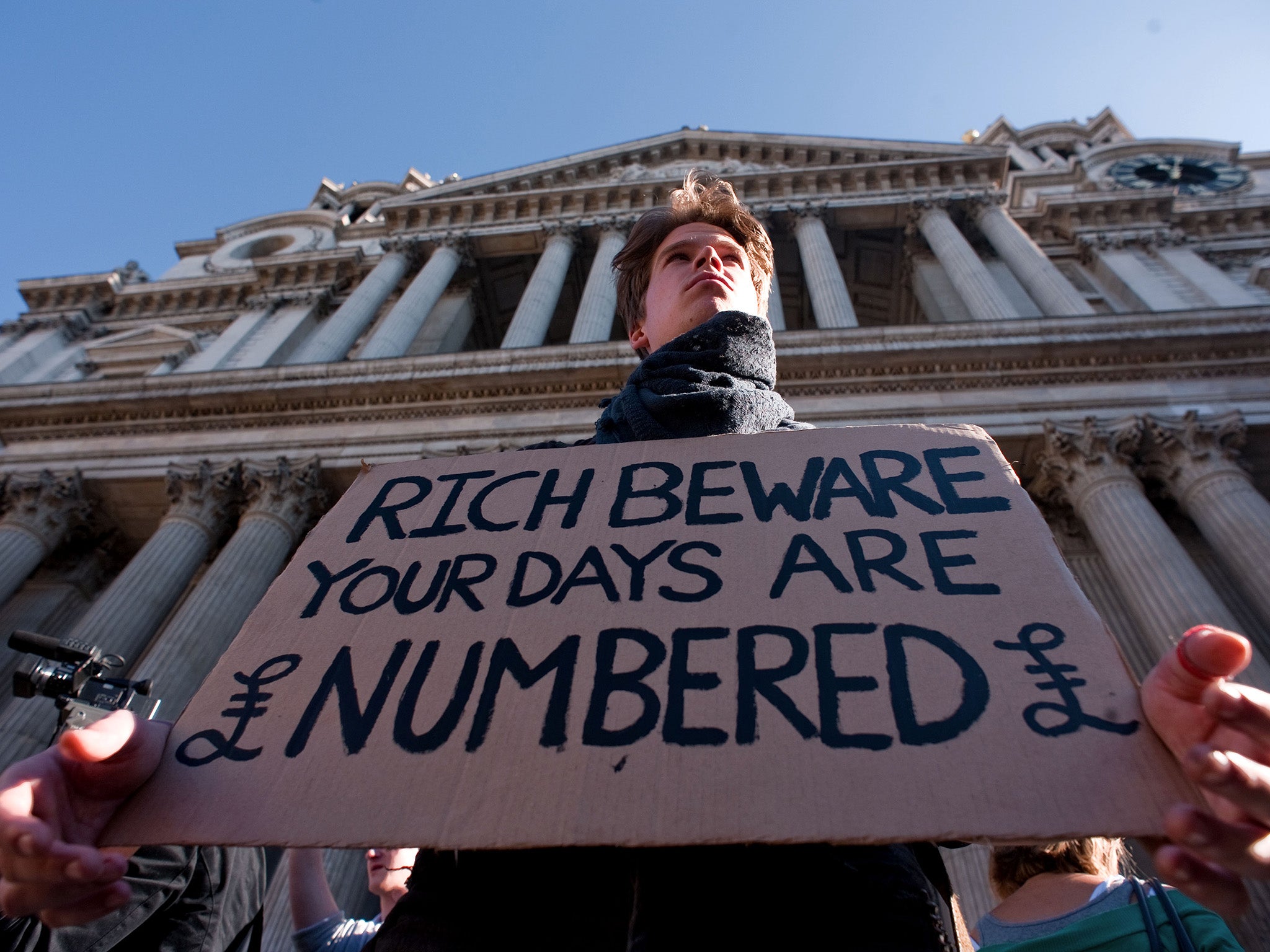 A protestor holds a placard on the steps of St Paul's cathedral in central London