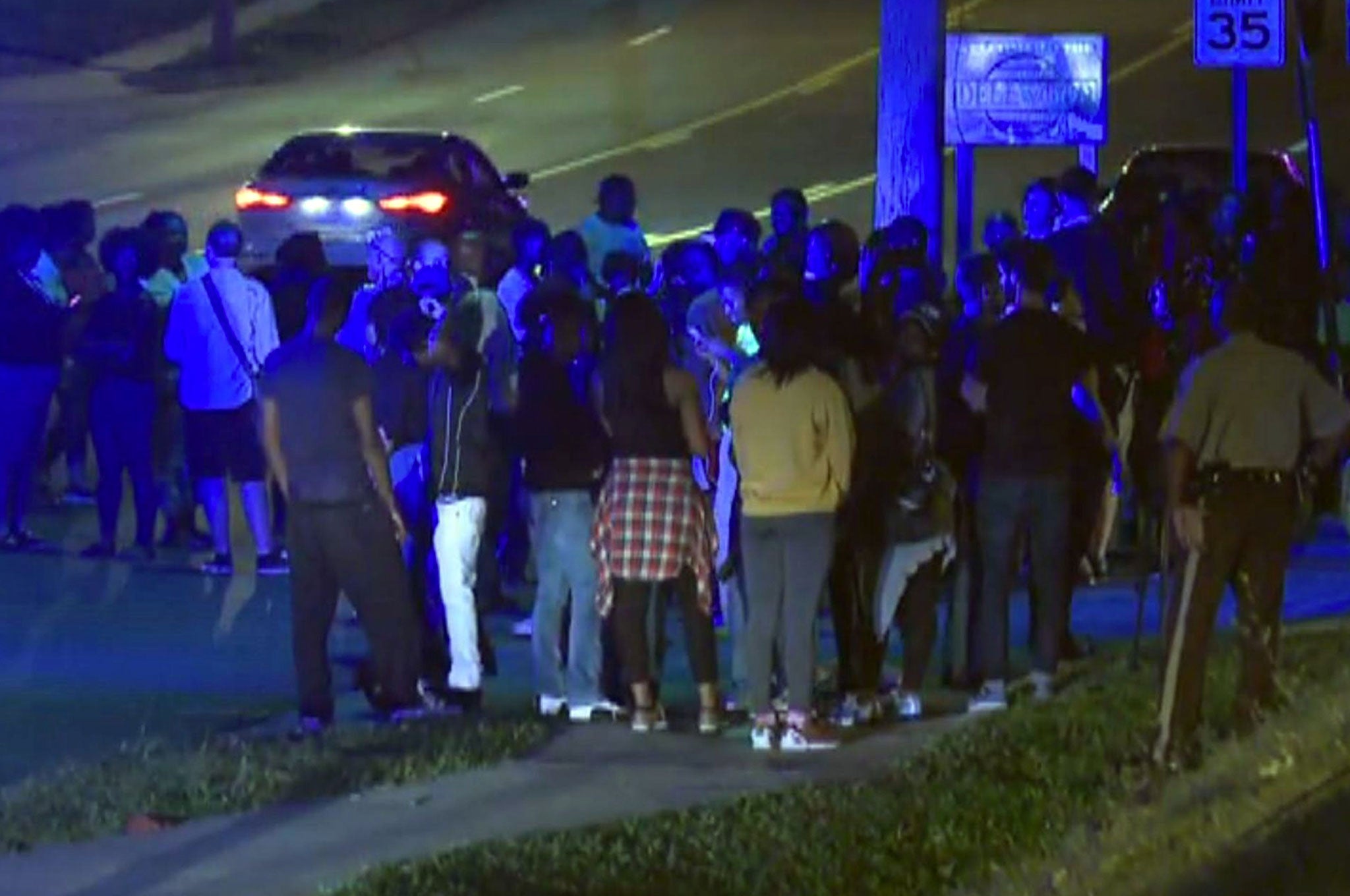 Police watch as crowds gather near the scene where a police officer was shot in the arm in Ferguson, Missouri