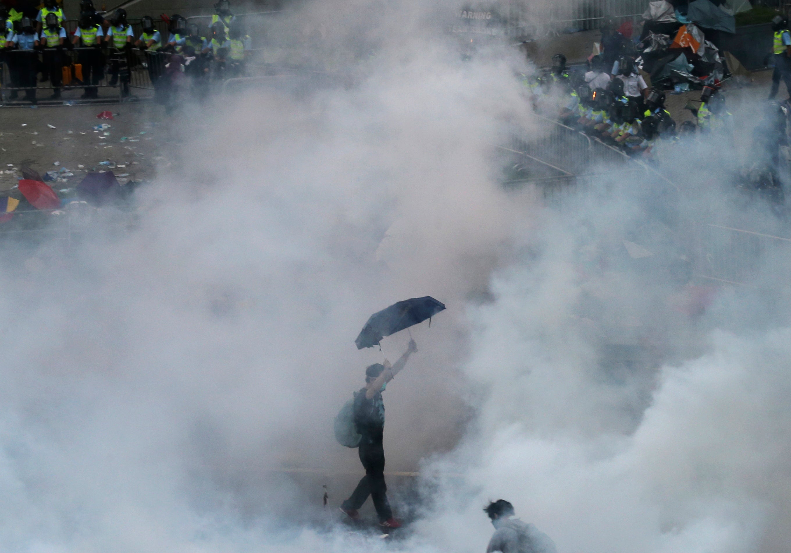 A protester walks in tear gas fired by riot policemen on 28 September 2014