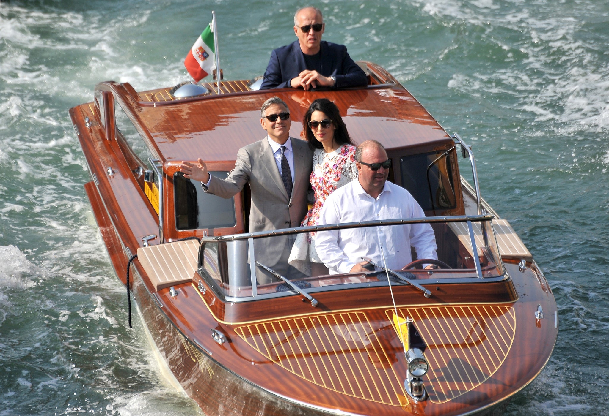 George Clooney and his wife Amal Alamuddin are surrounded by media and security boats as they tour the Grand Canal after leaving their hotel