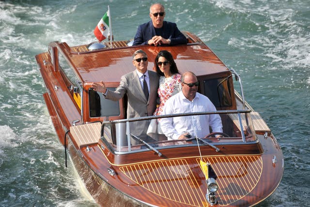 George Clooney and his wife Amal Alamuddin are surrounded by media and security boats as they tour the Grand Canal after leaving their hotel