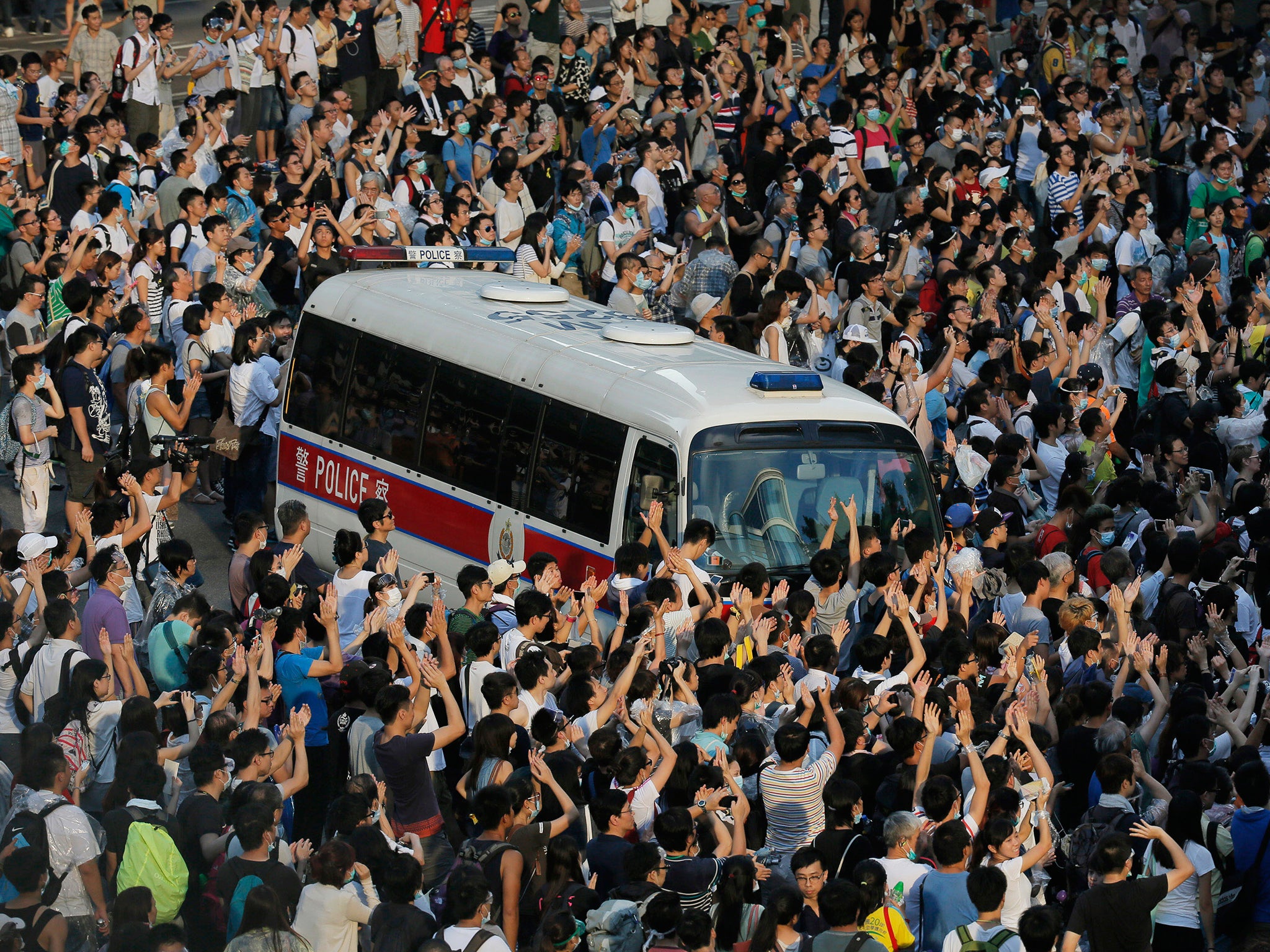 A police car is blocked by protesters after thousands of people block a main road to the financial central district outside the government headquarters in Hong Kong