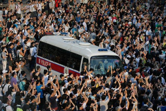 A police car is blocked by protesters after thousands of people block a main road to the financial central district outside the government headquarters in Hong Kong 