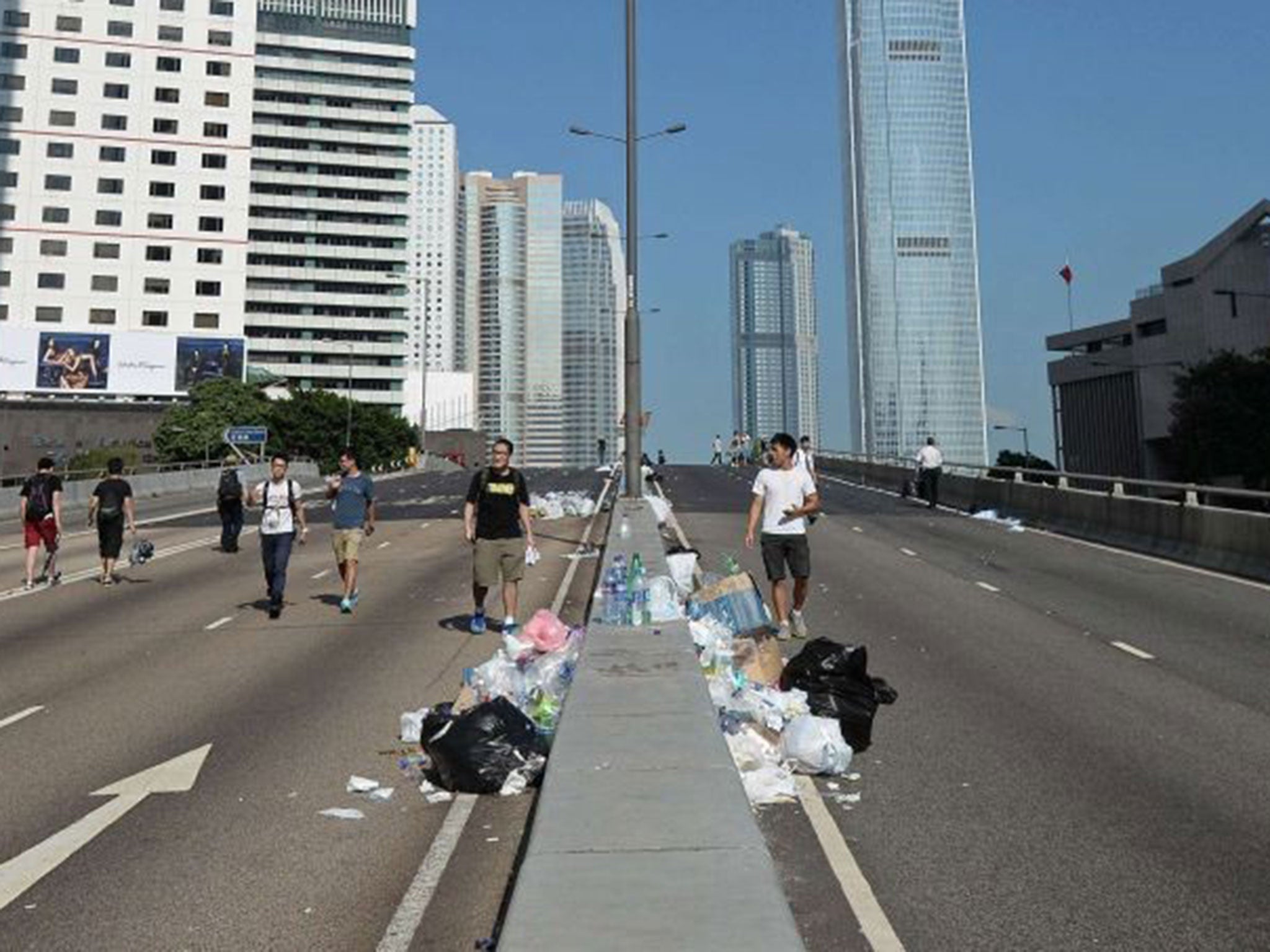 People walk along a closed road near the site of a pro-democracy protest near the Hong Kong government headquarters on September 29, 2014.