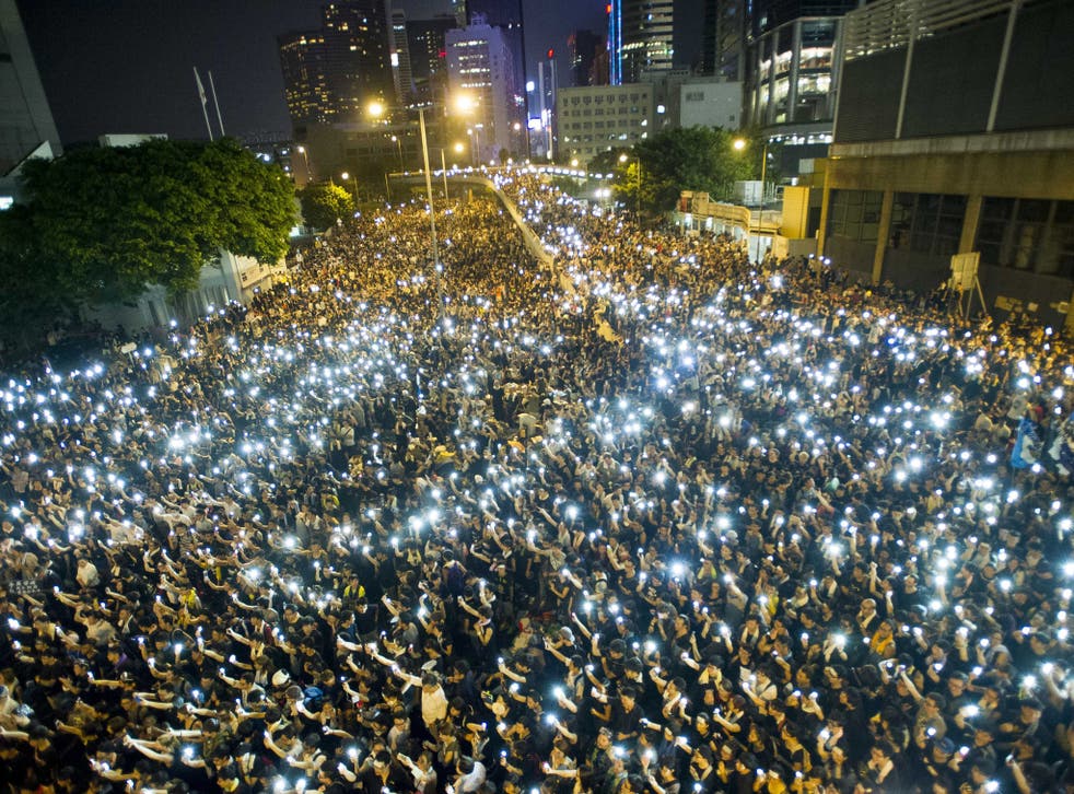 Protestors and student demonstrators hold up their cellphones in a display of solidarity during a protest outside the headquarters of Legislative Council in Hong Kong