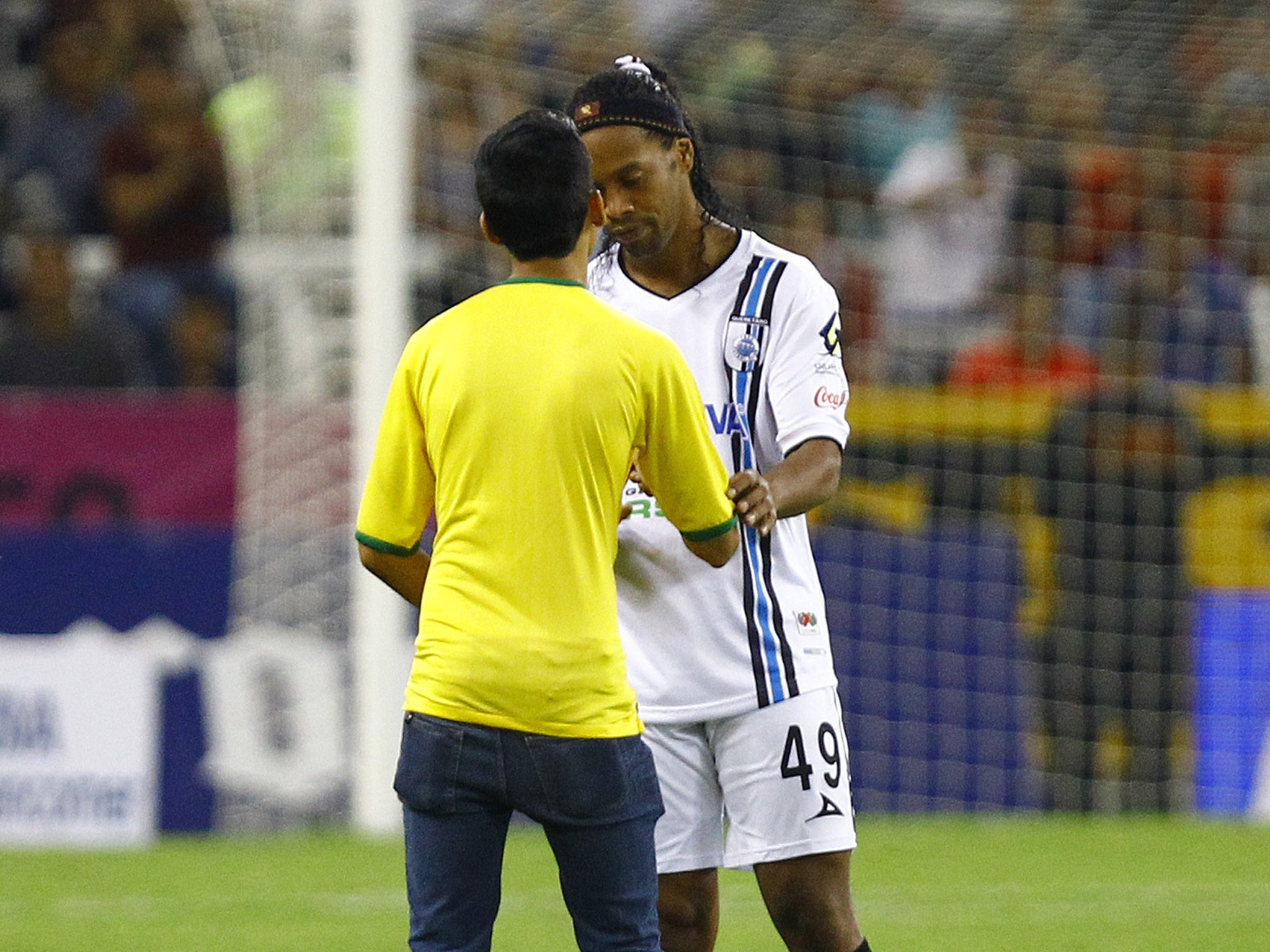 Ronaldinho signs the t-shirt of a pitch invader