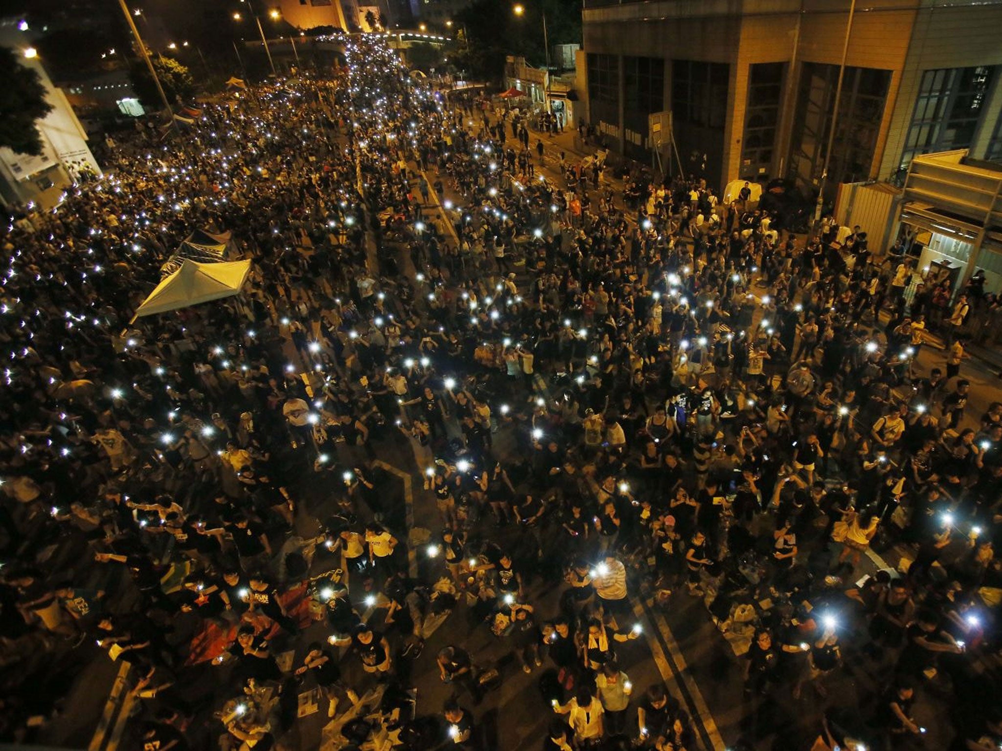 Tens of thousands of pro-democracy demonstrators, some waving lights from mobile phones, fill the streets in the main finical district of Hong Kong, on Wednesday