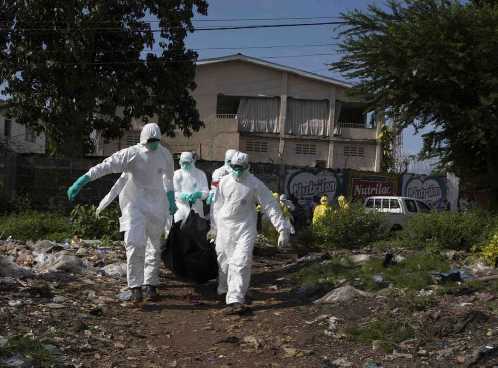 A burial team in protective clothing remove a body in Sierra Leone. Five people are being infected every hour.