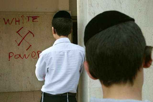 Destructive discourse: Jewish boys look at anti-Semitic graffiti sprayed on to the walls of the synagogue in March 2006, near Tel Aviv  