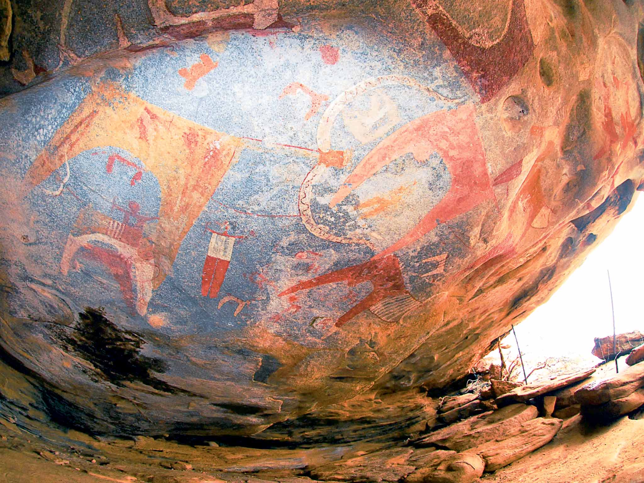 The painted roof of a low cave in Somaliland, which could be 3,000 years old, featuring large cows with huge decorated horns and humans in shirts and red trousers