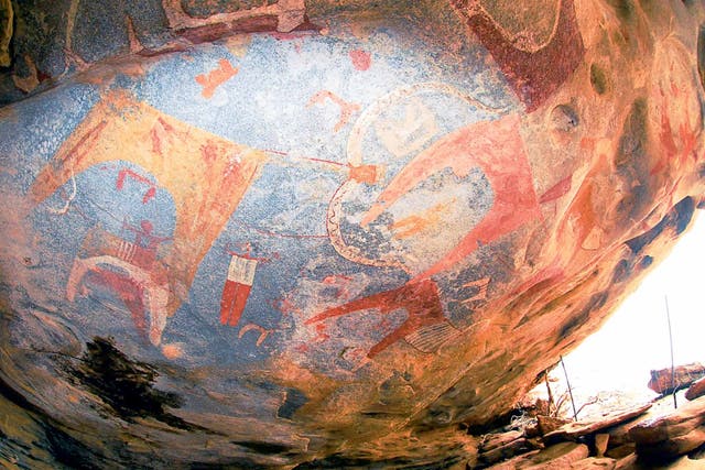 The painted roof of a low cave in Somaliland, which could be 3,000 years old, featuring large cows with huge decorated horns and humans in shirts and red trousers