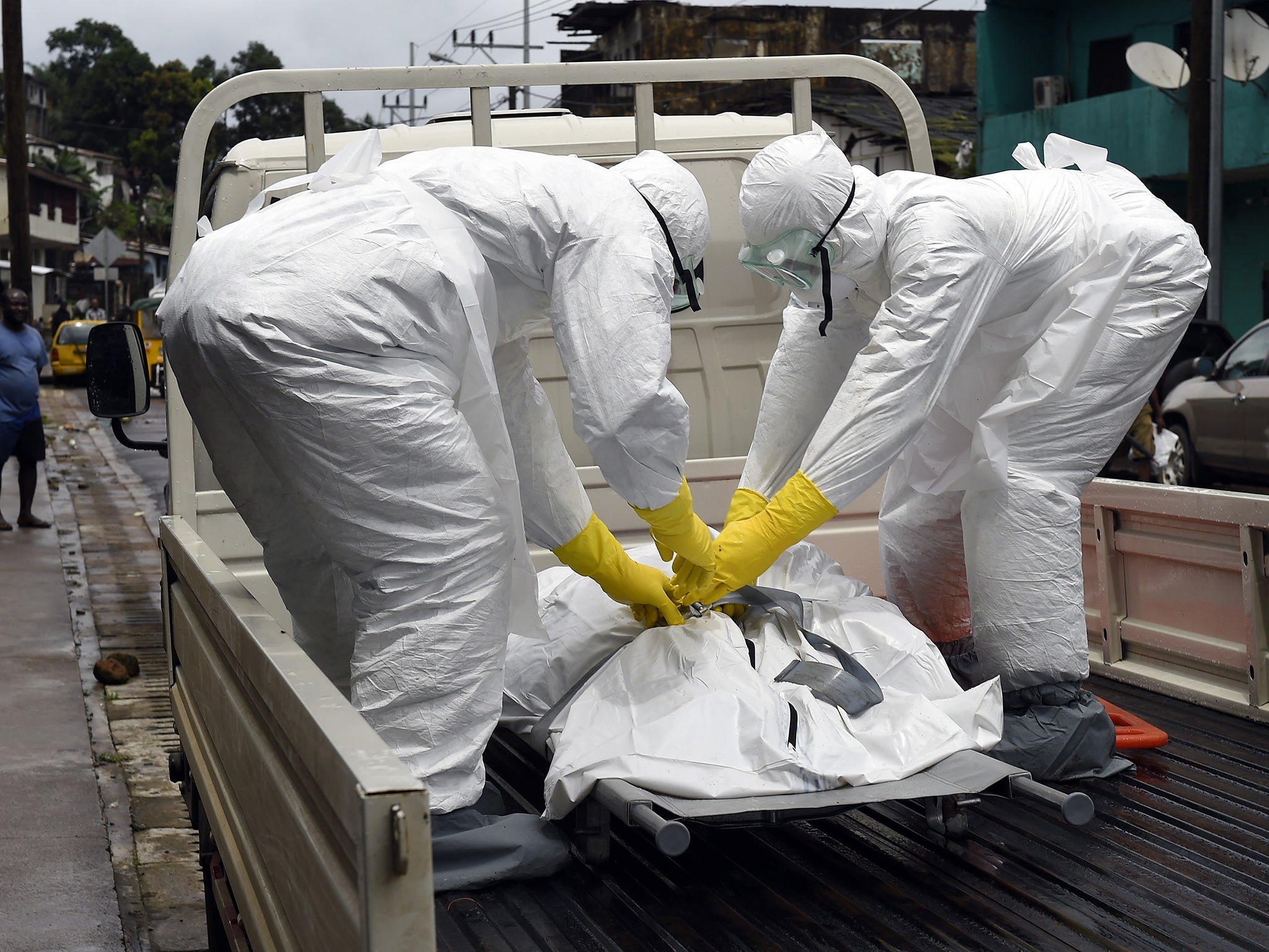 Medical staff members with the corpse of a victim of Ebola in Monrovia