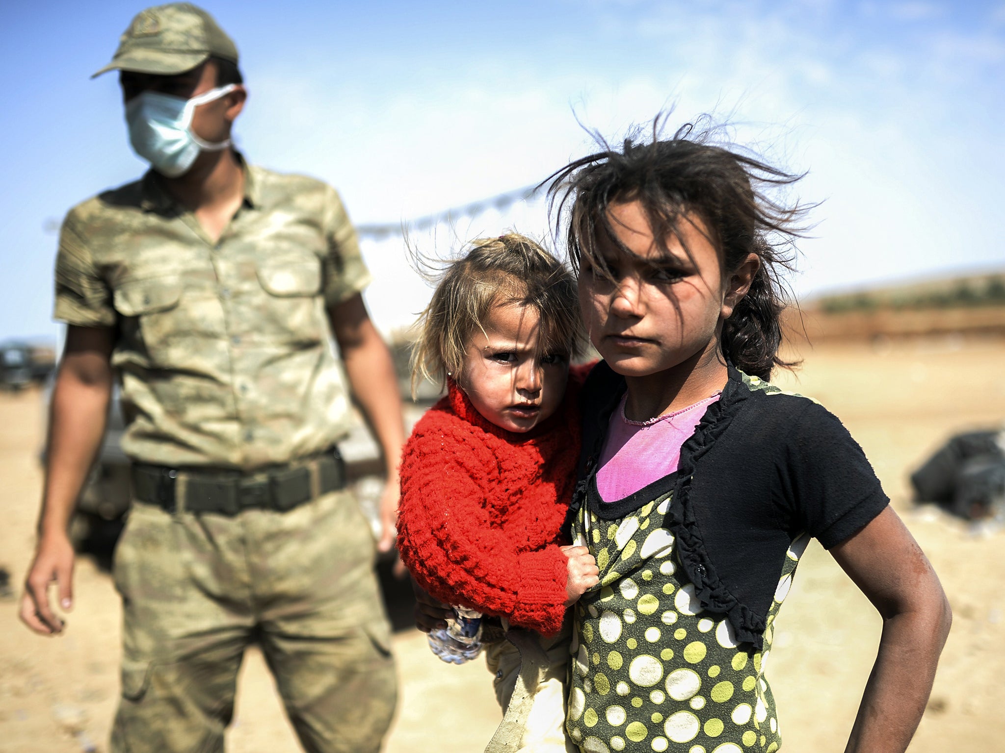 A Syrian Kurdish girl holds her sister in the southeastern town of Suruc in the Sanliurfa province after they crossed the border between Syria and Turkey