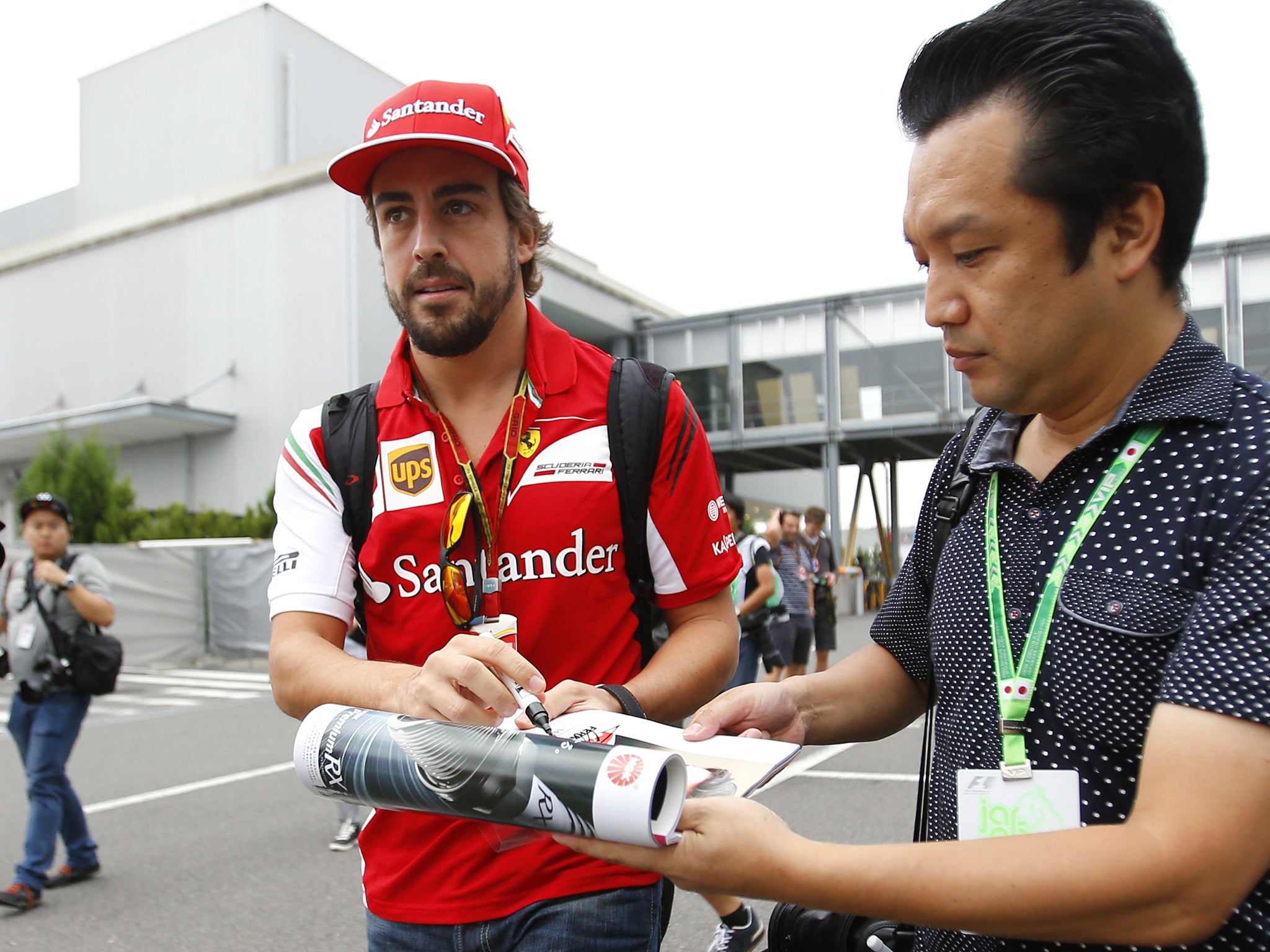 Fernando Alonso signs an autograph for a fan as he arrives at Suzuka to prepare for Sunday’s Japanese Grand Prix