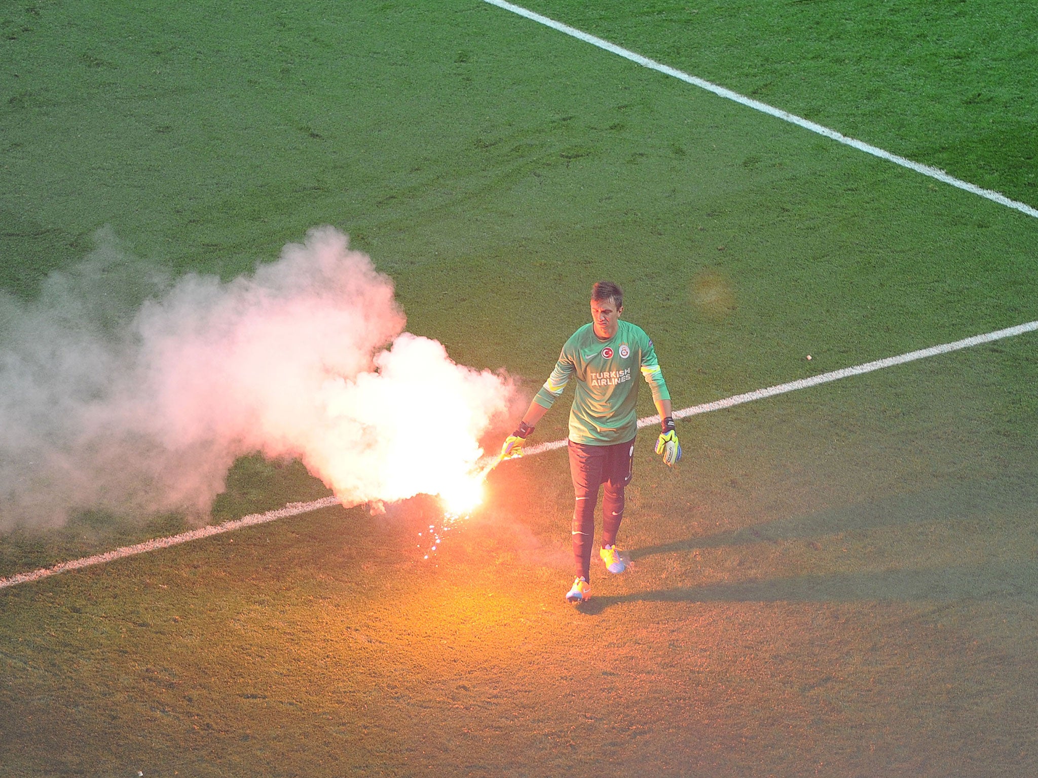 Galatasaray goalkeeper Fernando Muslera removes a burning flare from the pitch