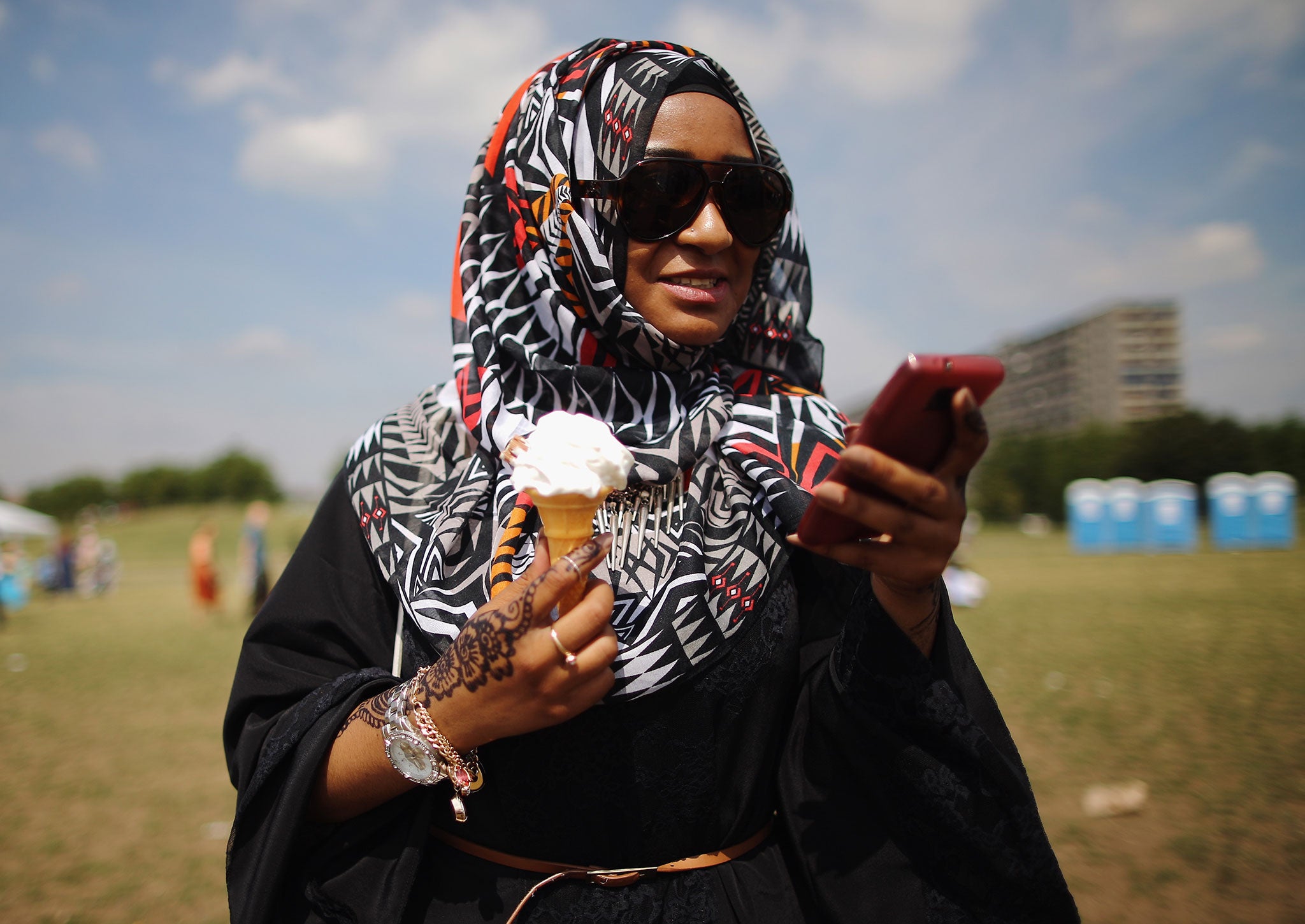 A Muslim woman enjoys an ice-cream during an Eid celebration fun fair in Burgess Park