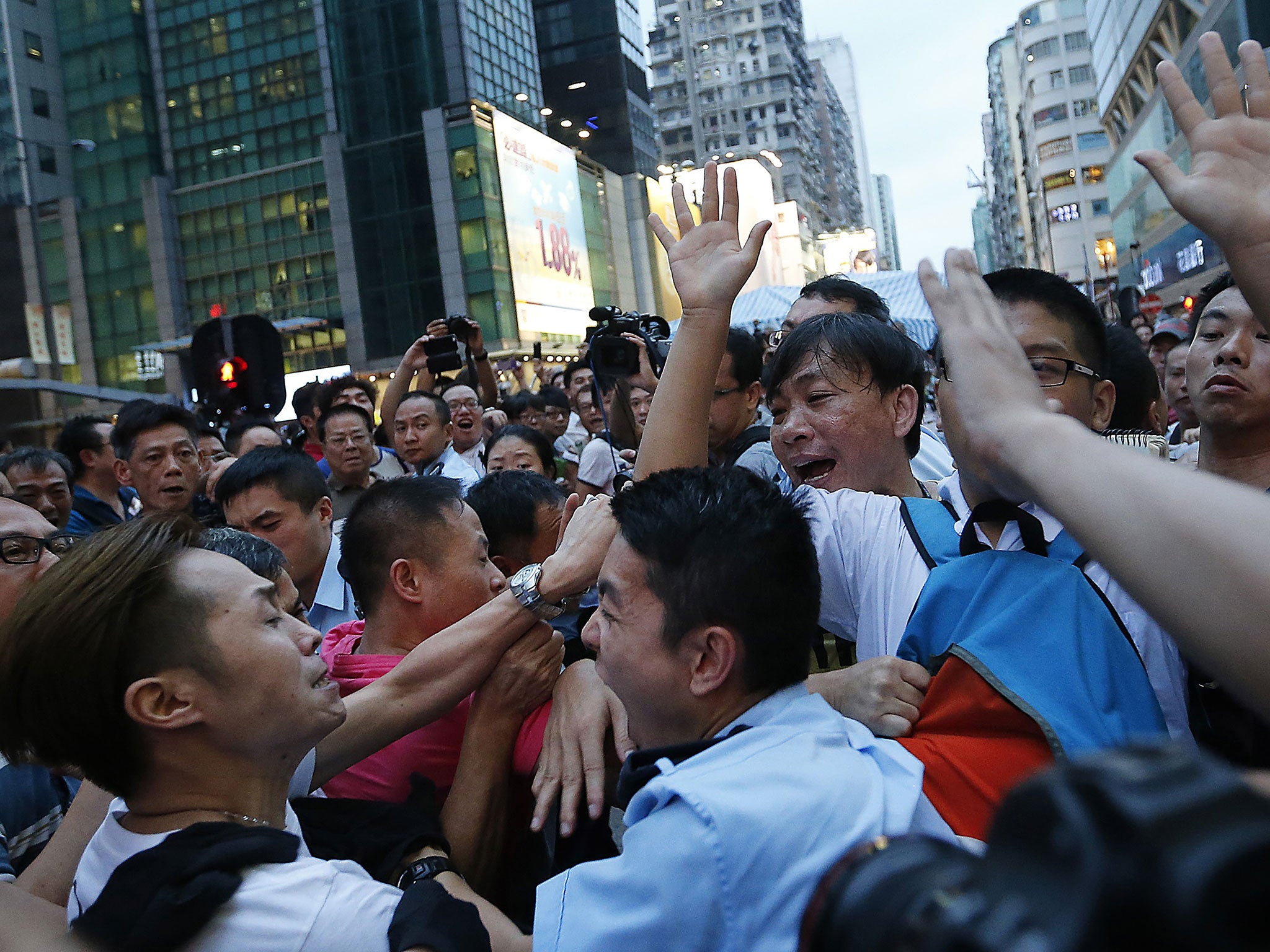 A local policeman scuffles with residents and pro-Beijing supporters as they try to attack a student pro-democracy activist in Kowloon's crowded Mong Kok district
