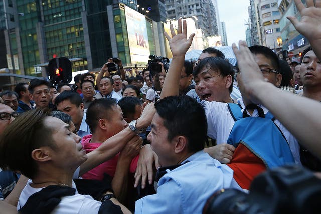 A local policeman scuffles with residents and pro-Beijing supporters as they try to attack a student pro-democracy activist in Kowloon's crowded Mong Kok district