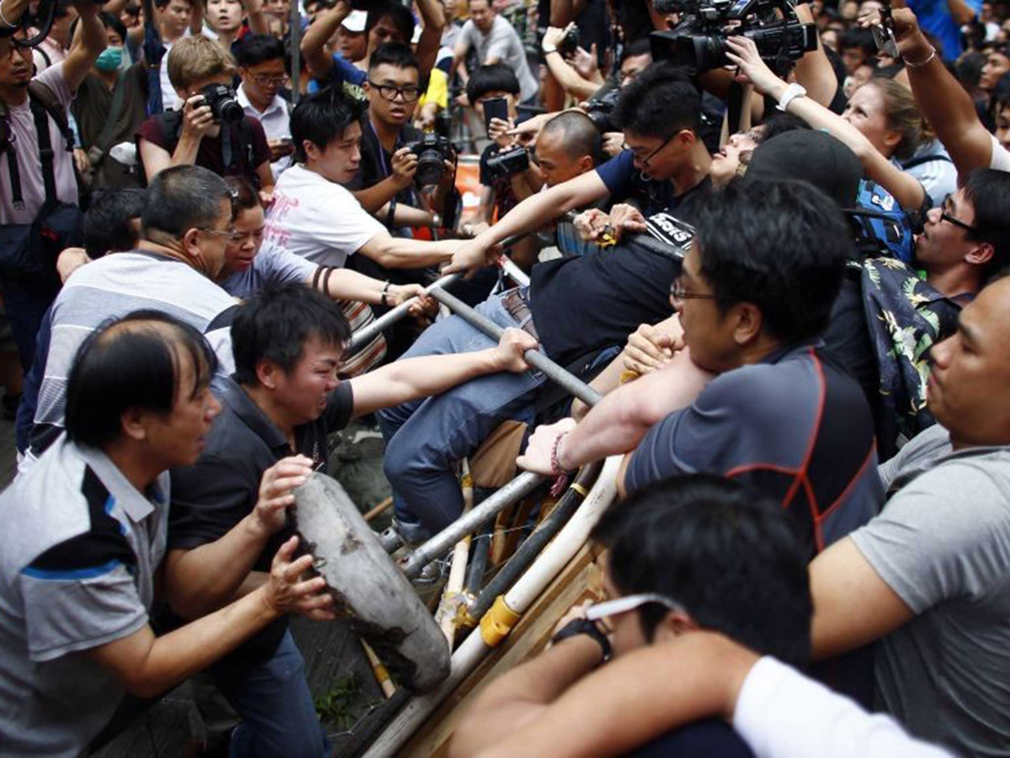 Anti-Occupy Central protesters (L) try to remove a barricade from pro-democracy protesters on a main street