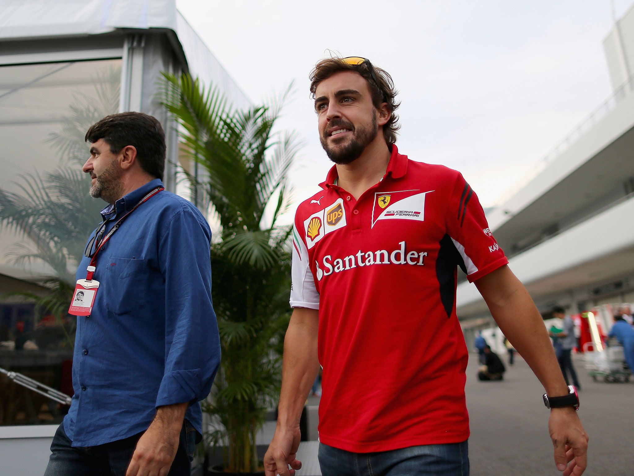 Fernando Alonso smiles as he walks through the paddock