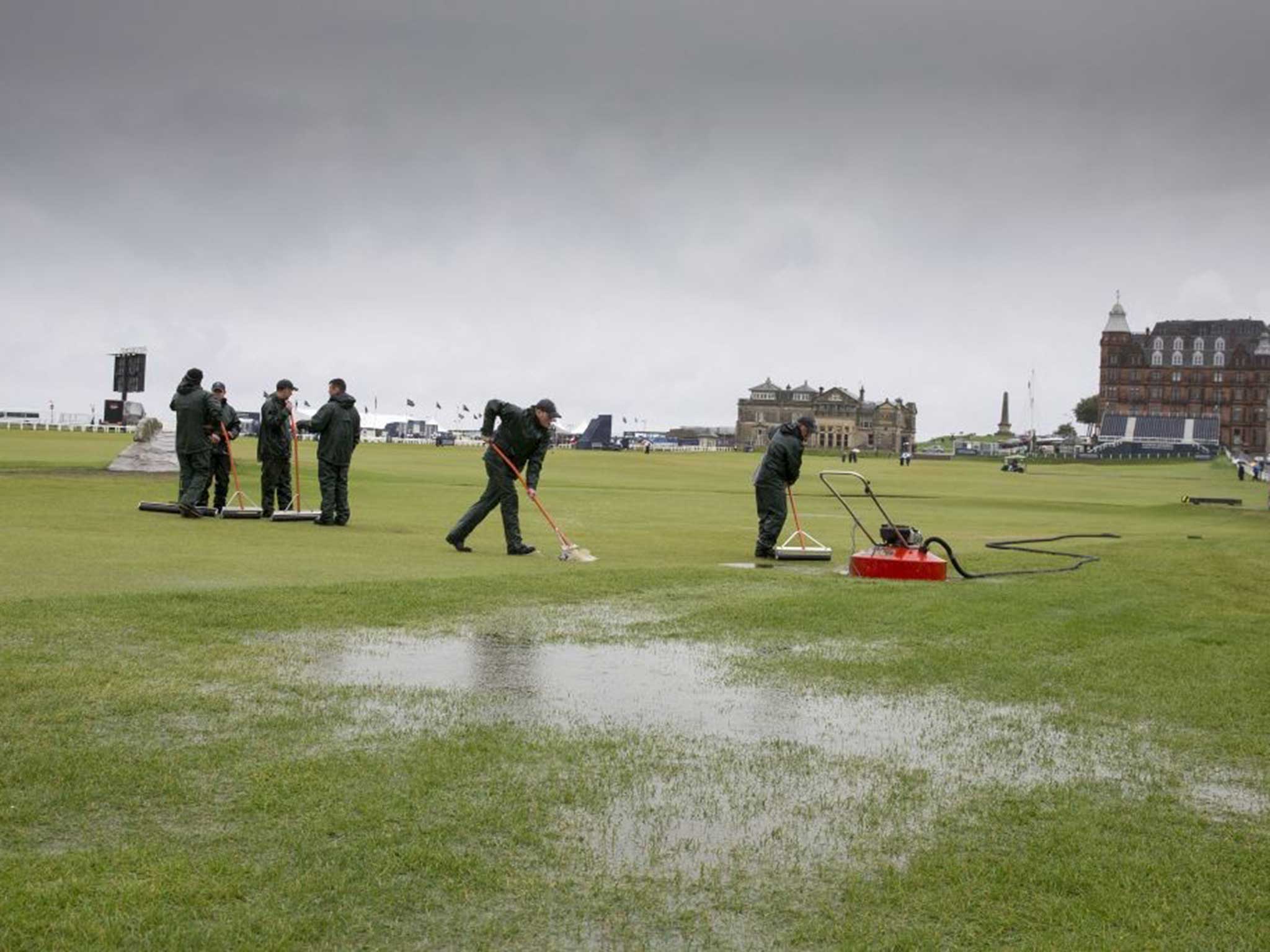 Ground staff work top clear water following heavy rain in St Andrews, Scotland