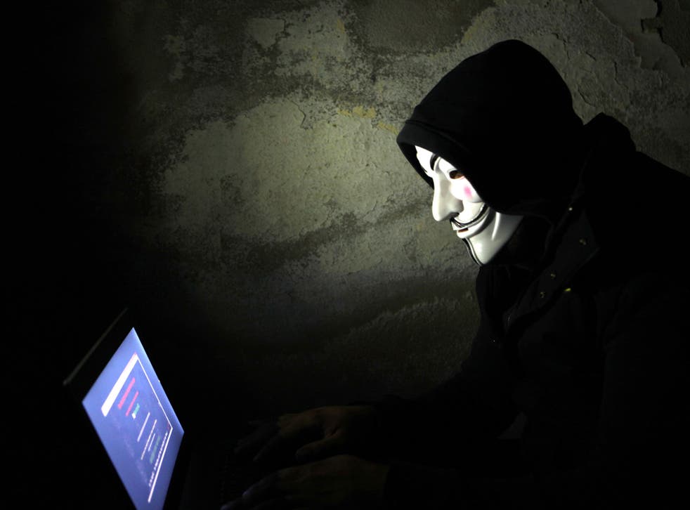 A wearing a Vendetta mask using a laptop